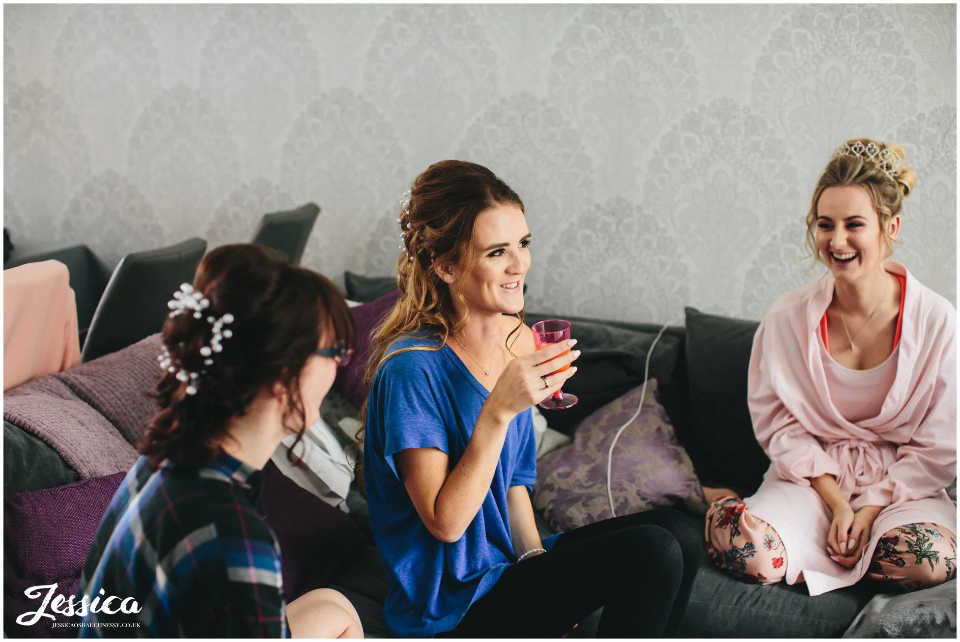 bride & bridesmaid laugh whilst getting ready for the wedding