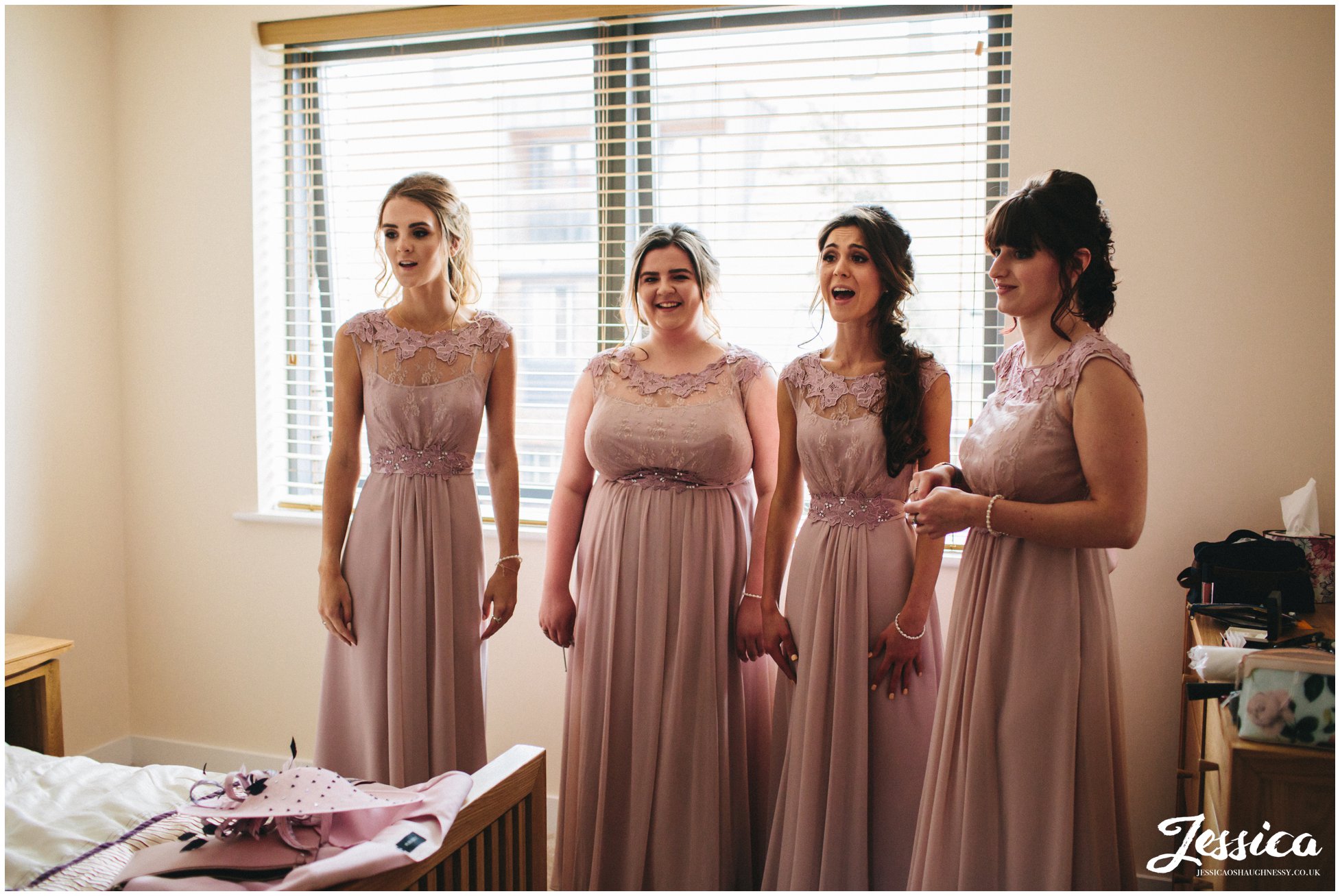 bridesmaids admire the bride as she gets into her dress