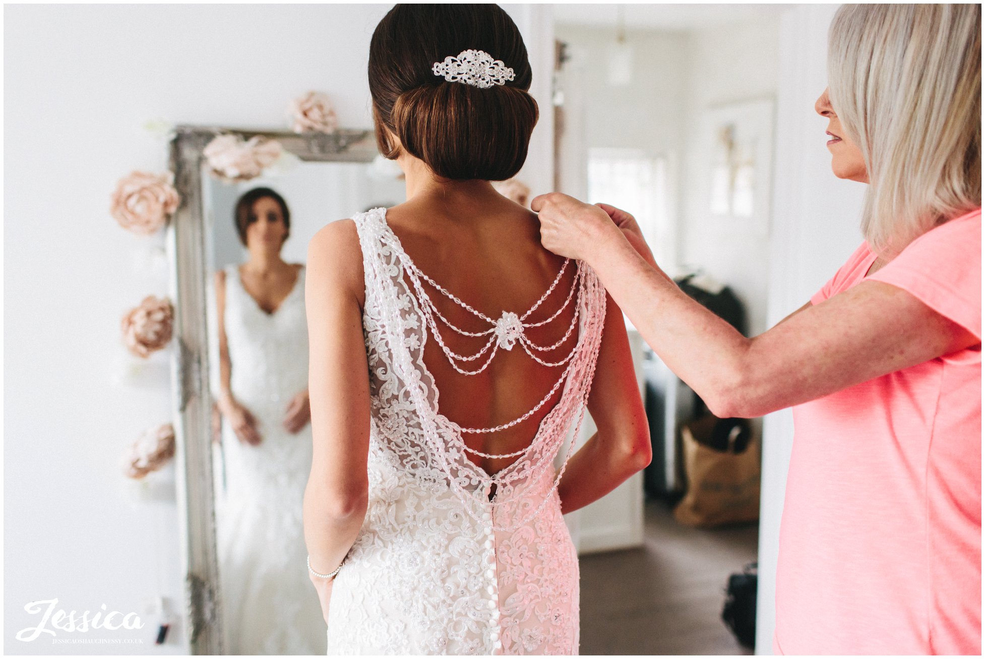 bride's mother helps her daughter into her wedding dress