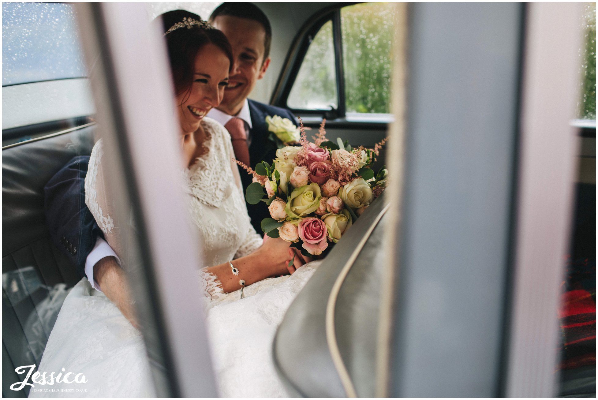 newly wed's laughing together in the back of their wedding car