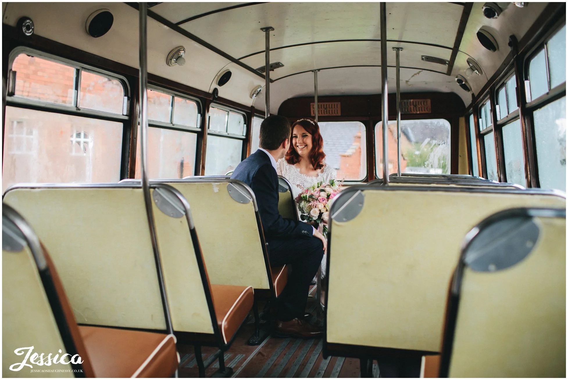 bride & groom shelter from the rain on the bus