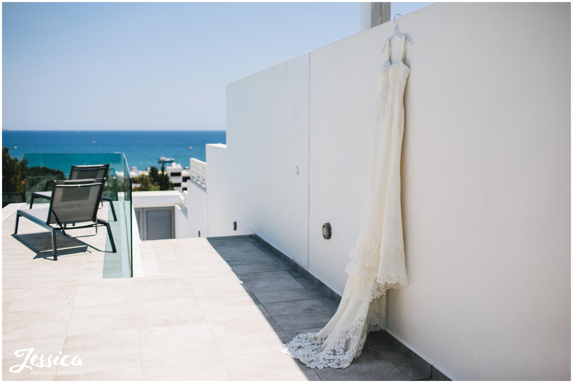wedding dress hung on the villa wall with the sea in the background
