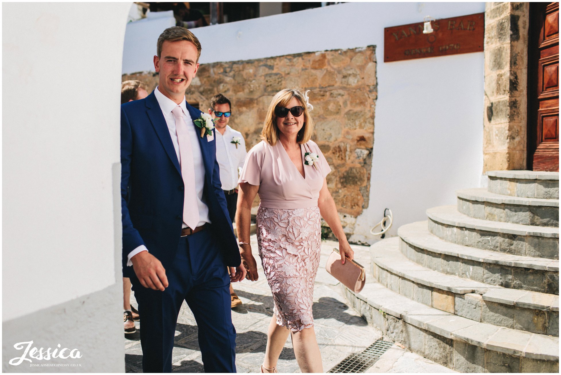 the groom and his mother walk through lindos to st pauls bay