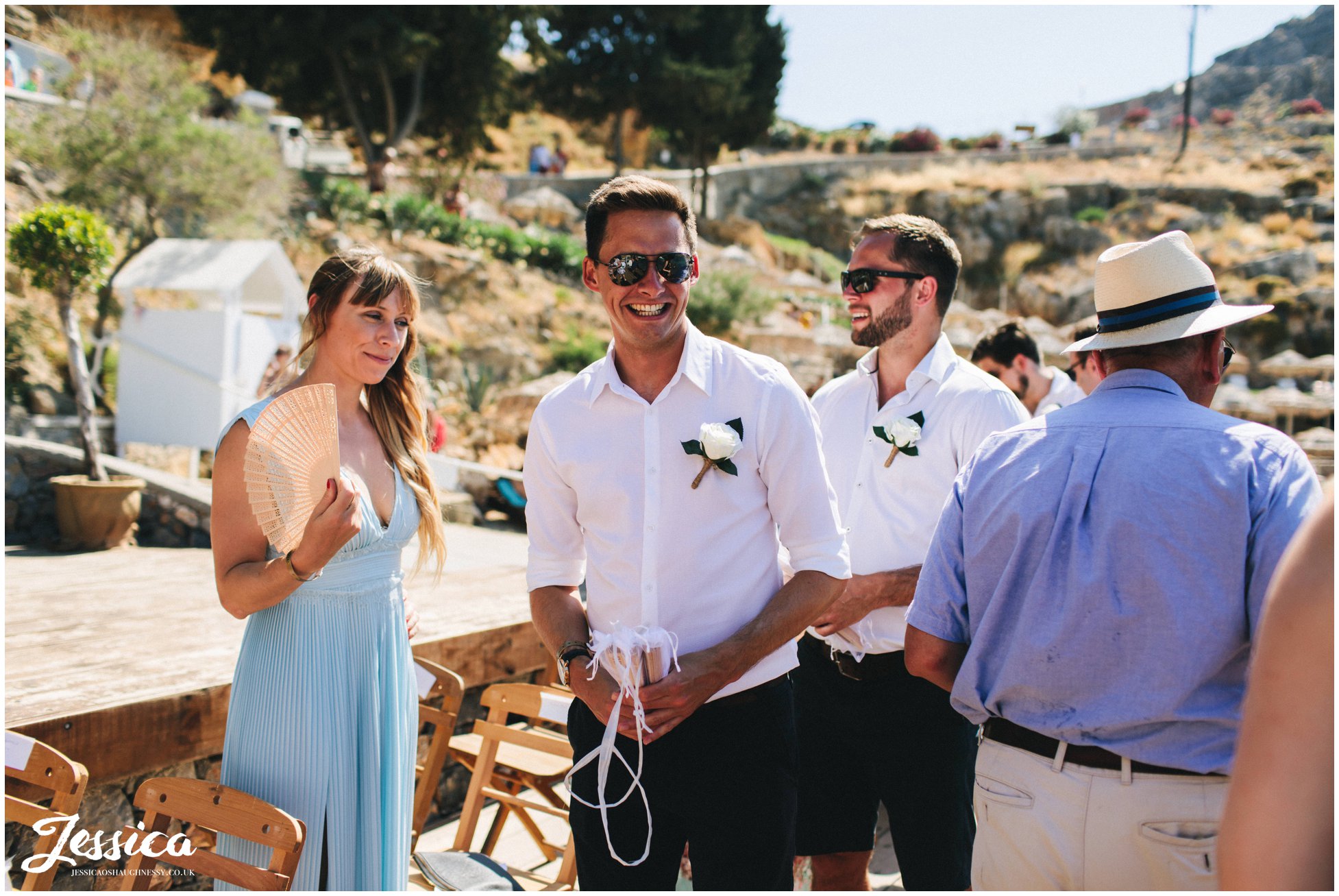 groomsmen hand out fan's for the wedding guests