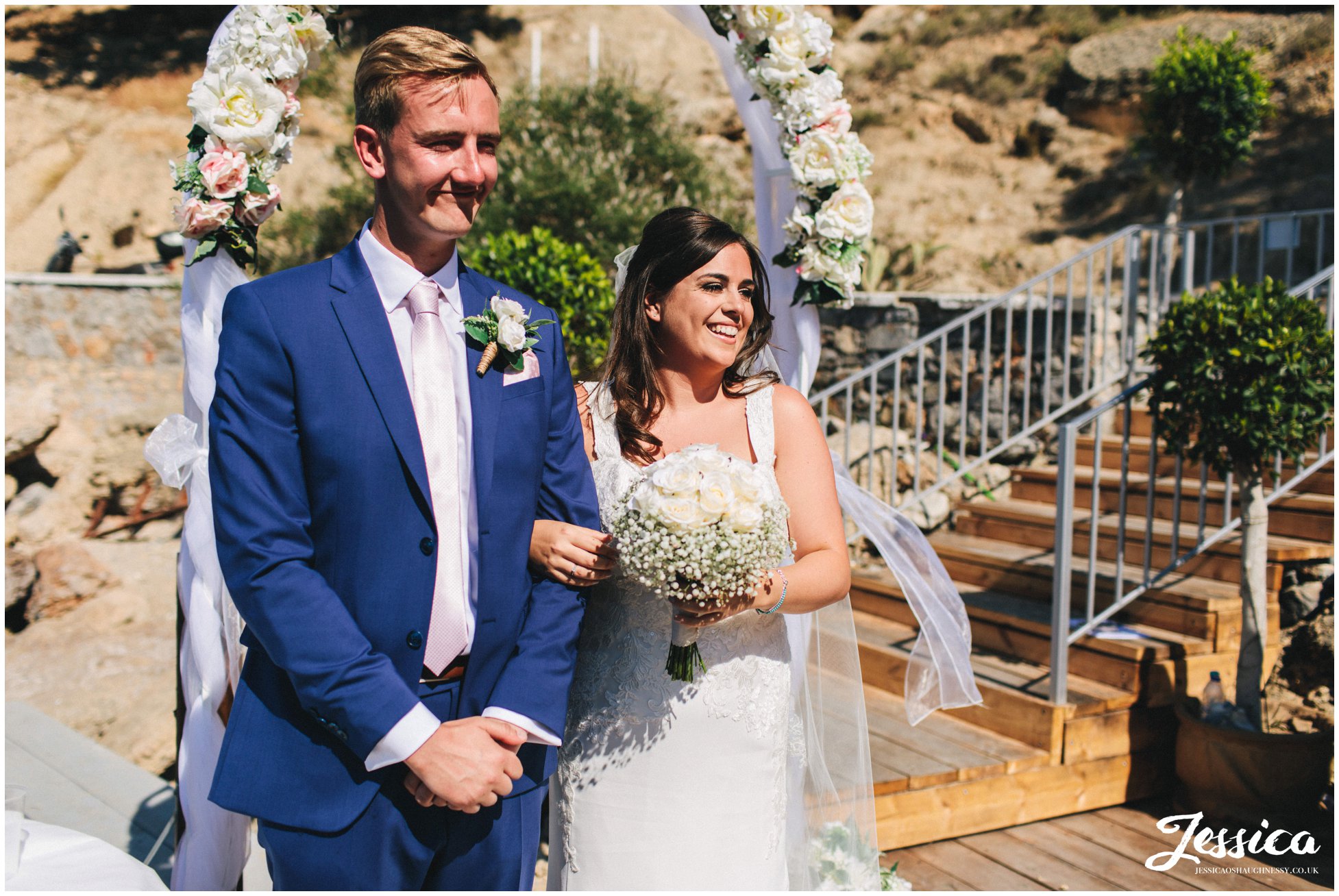 bride & groom smile as their guests give a reading