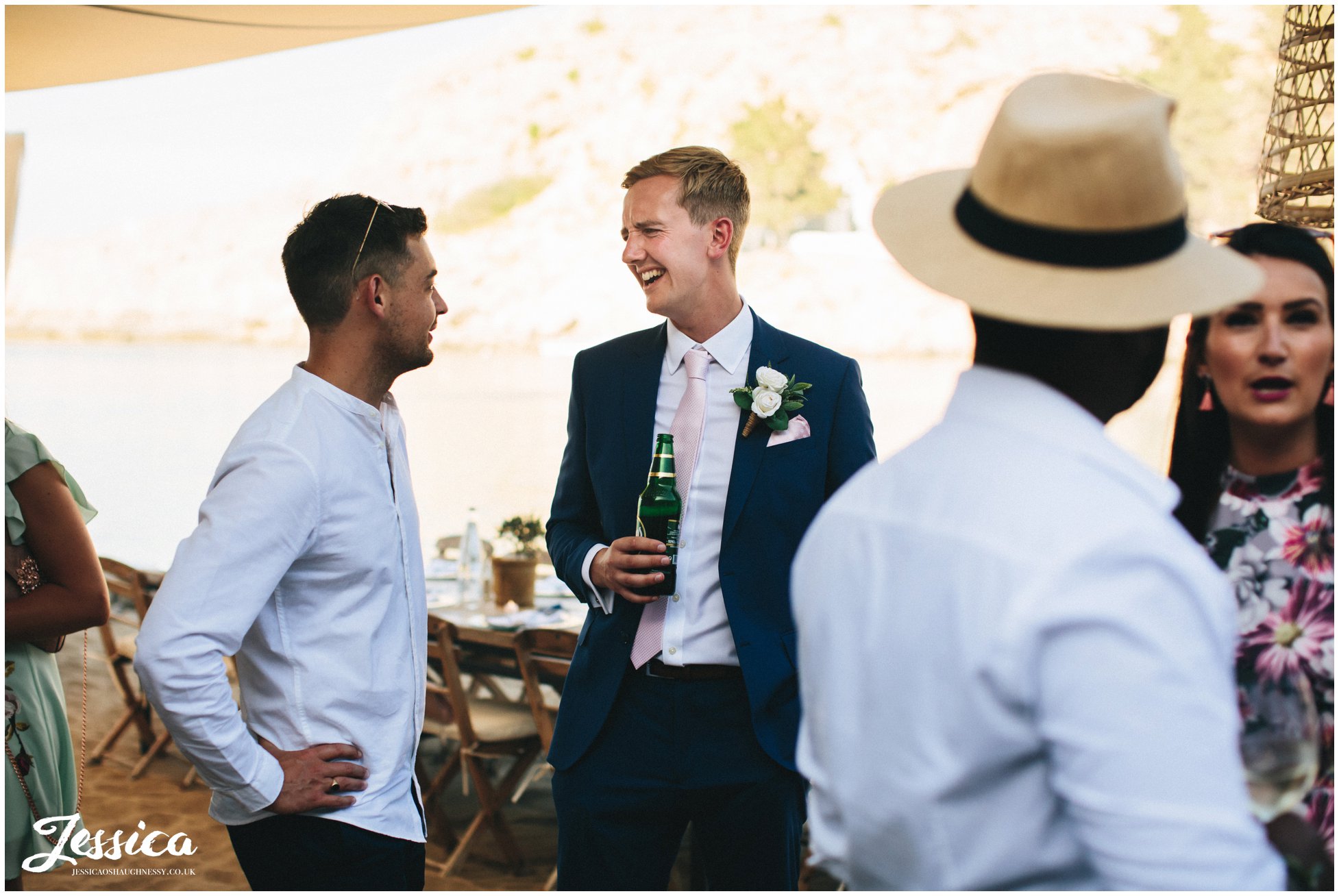 the groom jokes with his friends at their wedding reception