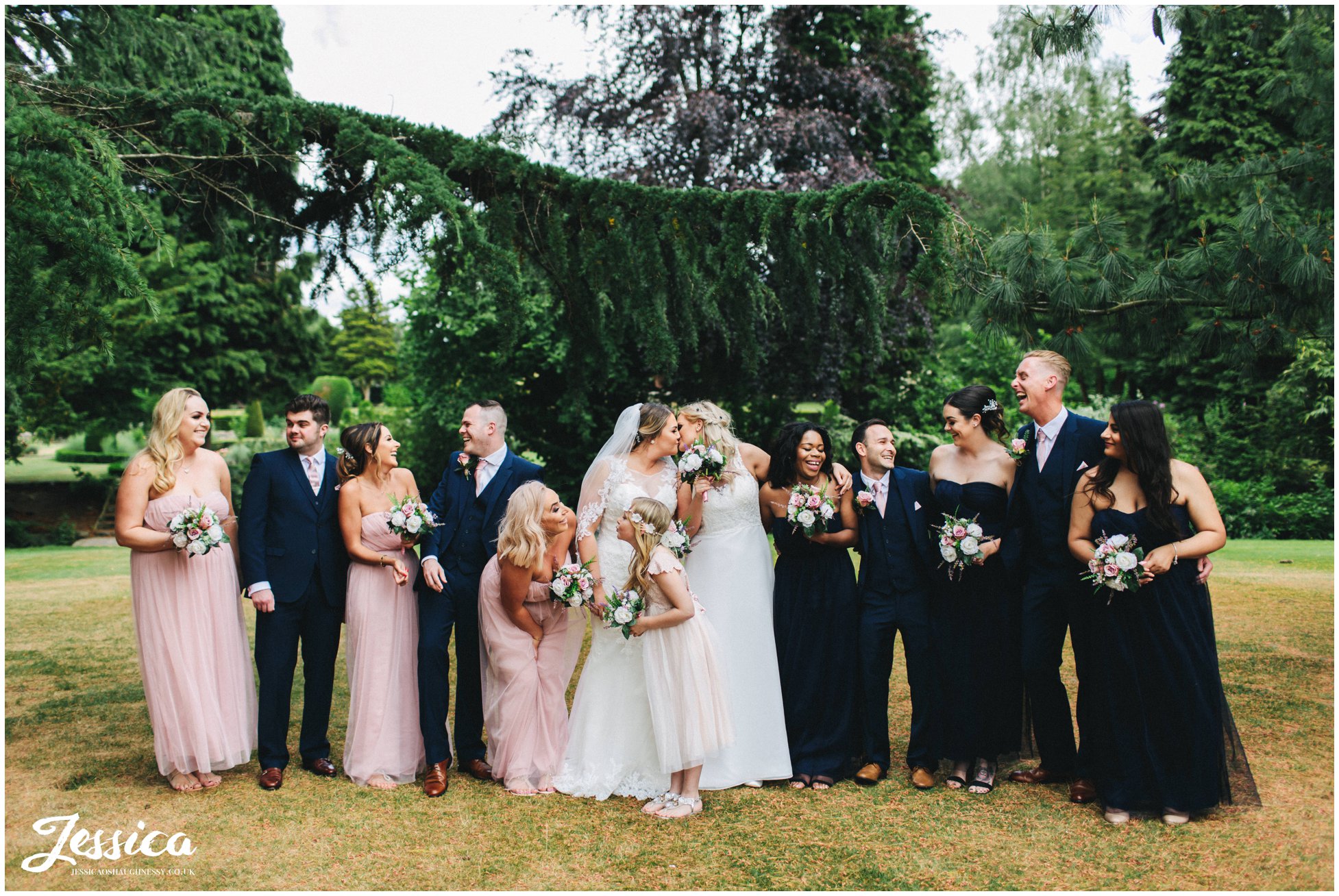 brides & their wedding party laugh together in the gardens