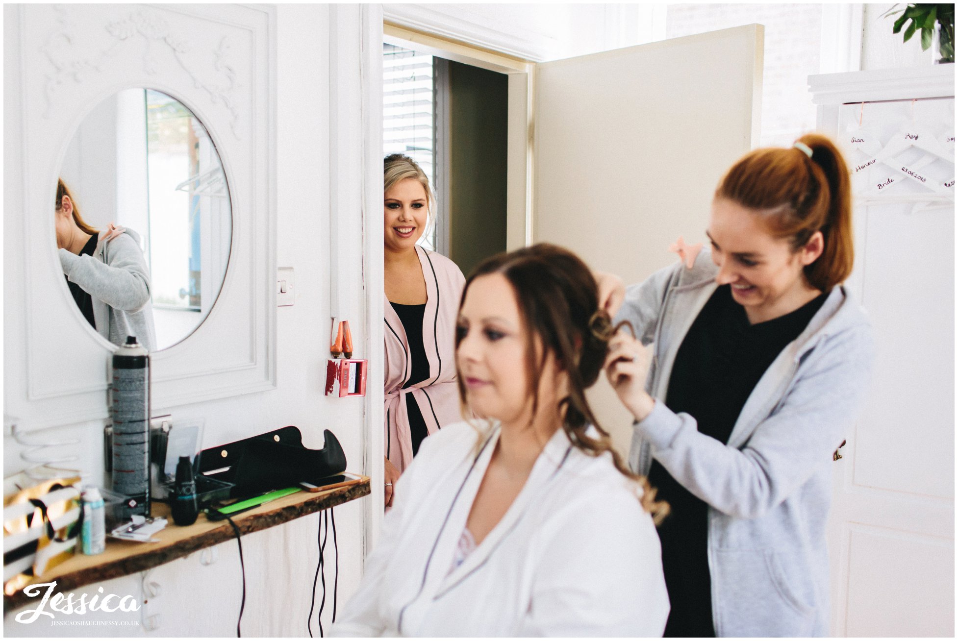 sister of the bride watches her having her make-up done for the ceremony