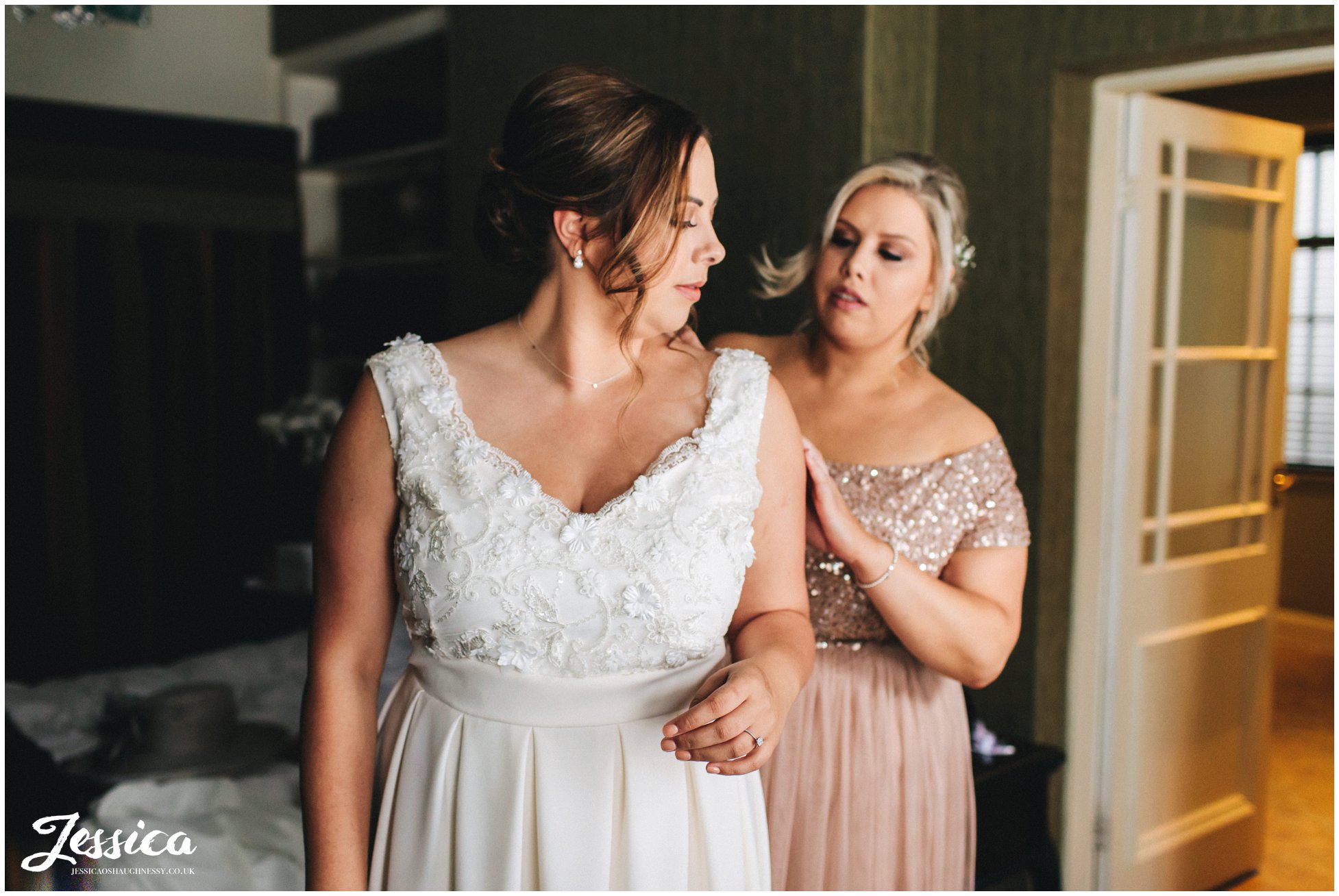 sister helps the bride into her wedding dress