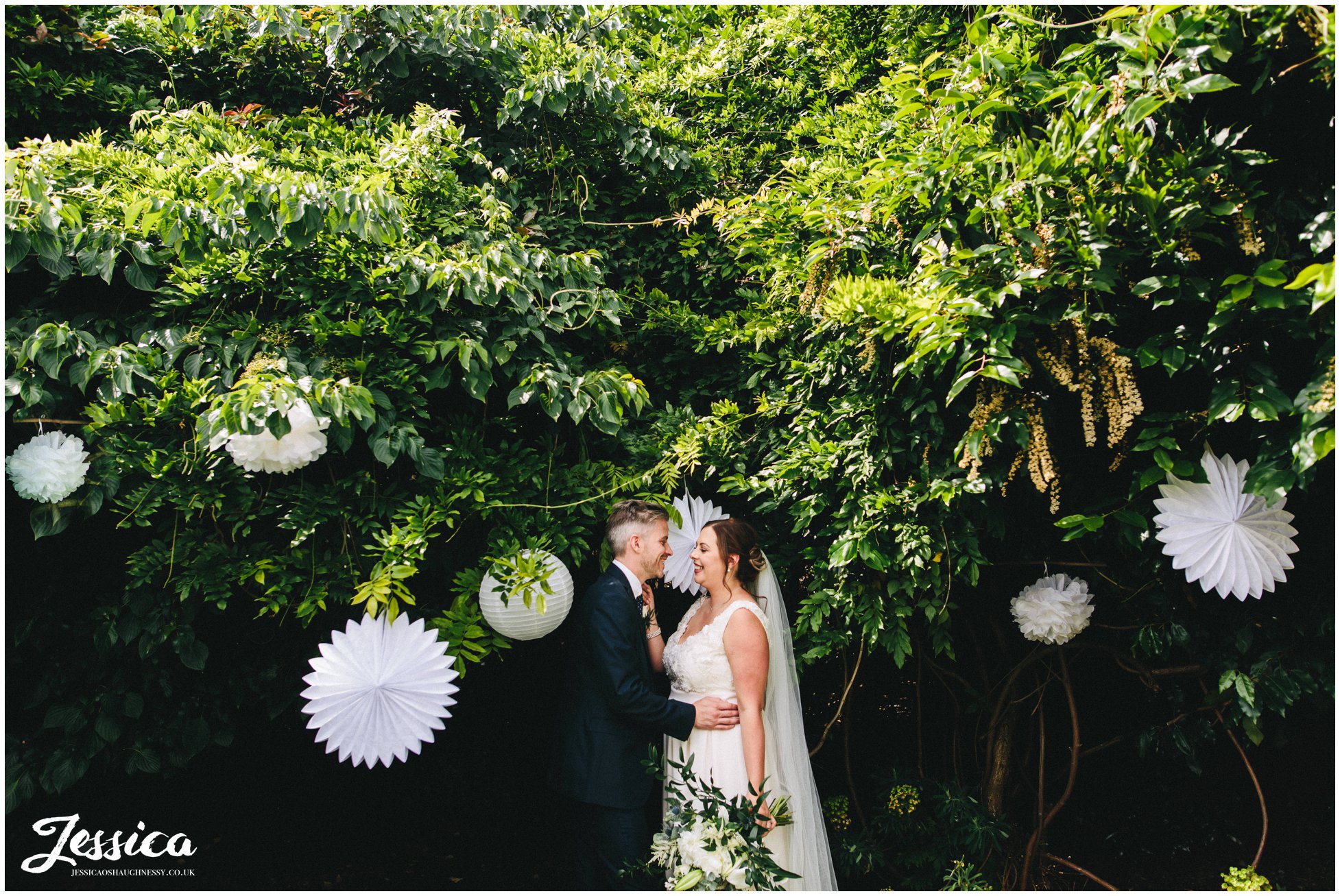 the couple kiss in front of the gardens decorated with paper lanterns