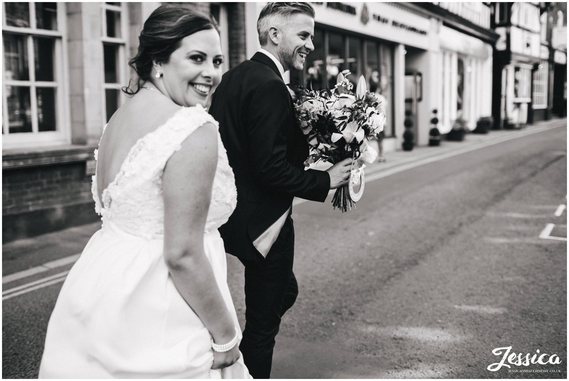 the groom carries the brides bouquet for her whilst walking down the street