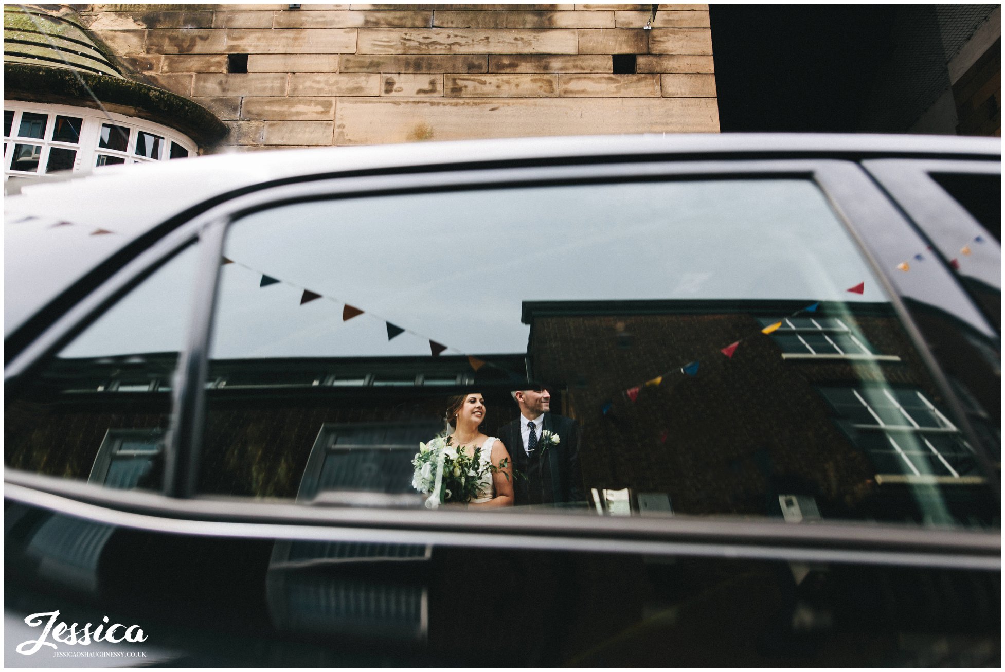 bride & groom photographed through a car window on the busy street