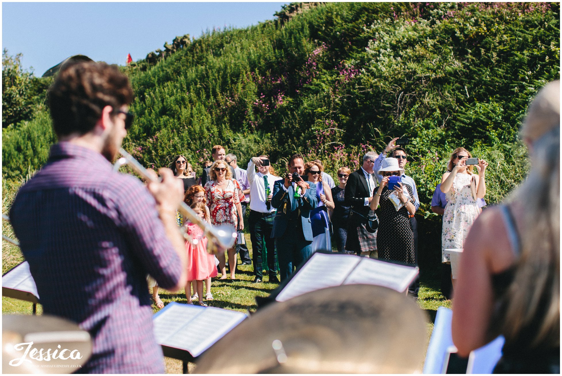 wedding guests enjoy the brass band playing by Caernarfon bay