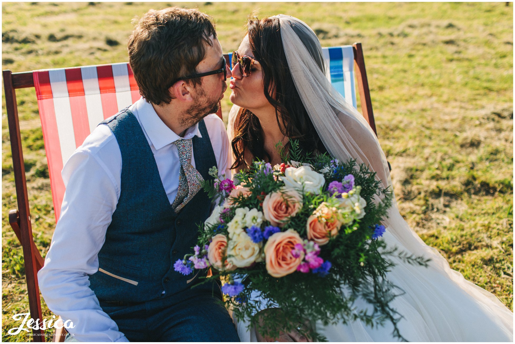 bride & groom pose on the deck chairs with sunglasses on