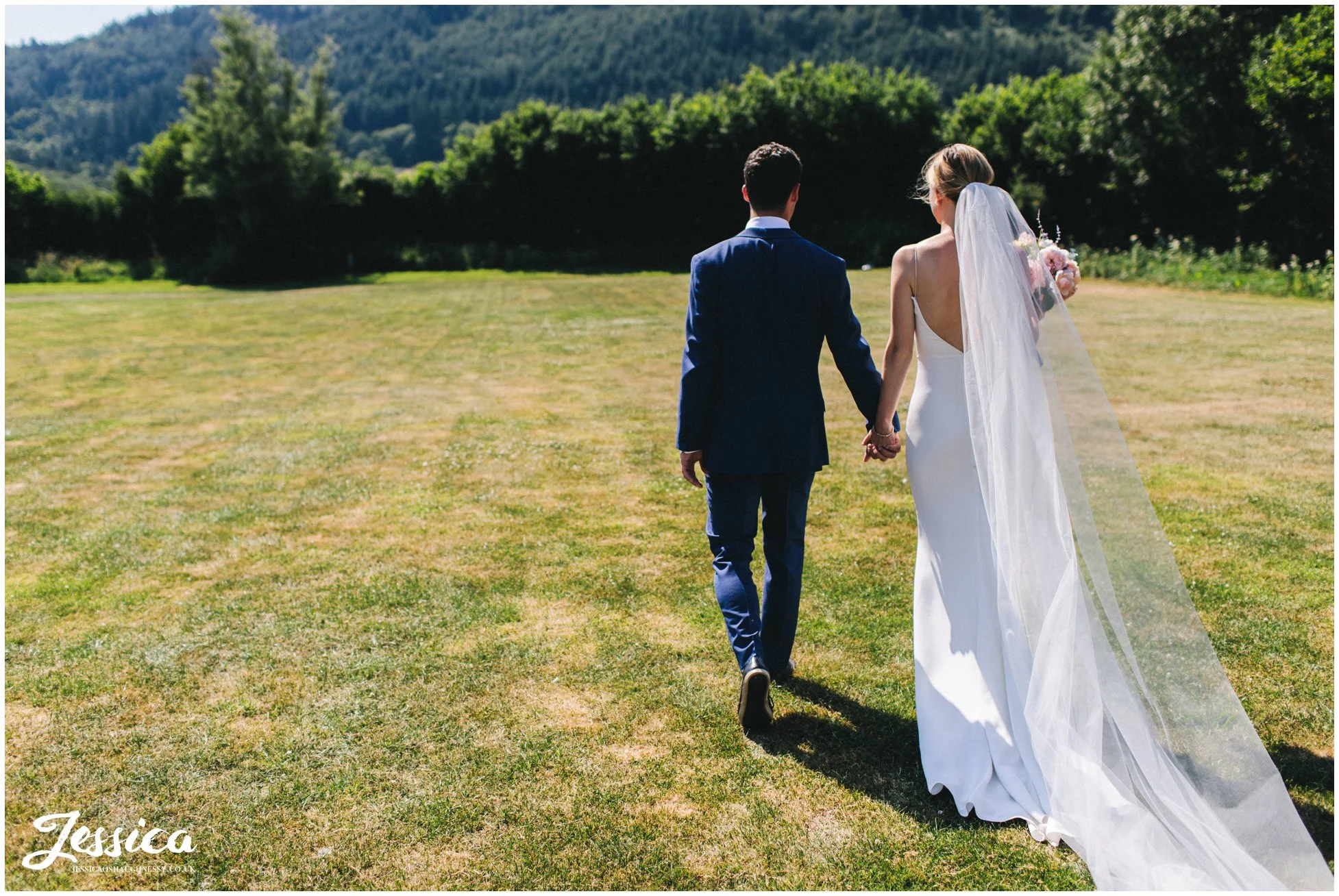 the couple walk hand in hand through the north wales fields