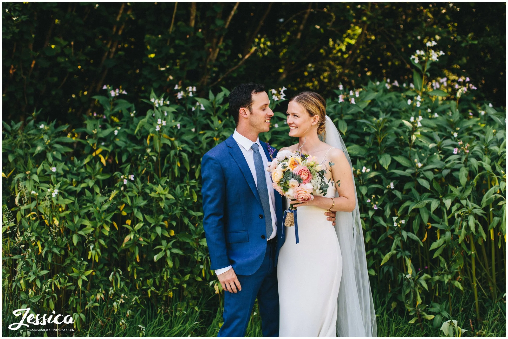 the couple smile at each other before their wedding ceremony