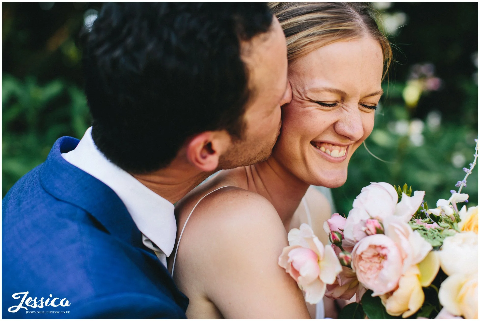 the groom kisses the bride as she laughs