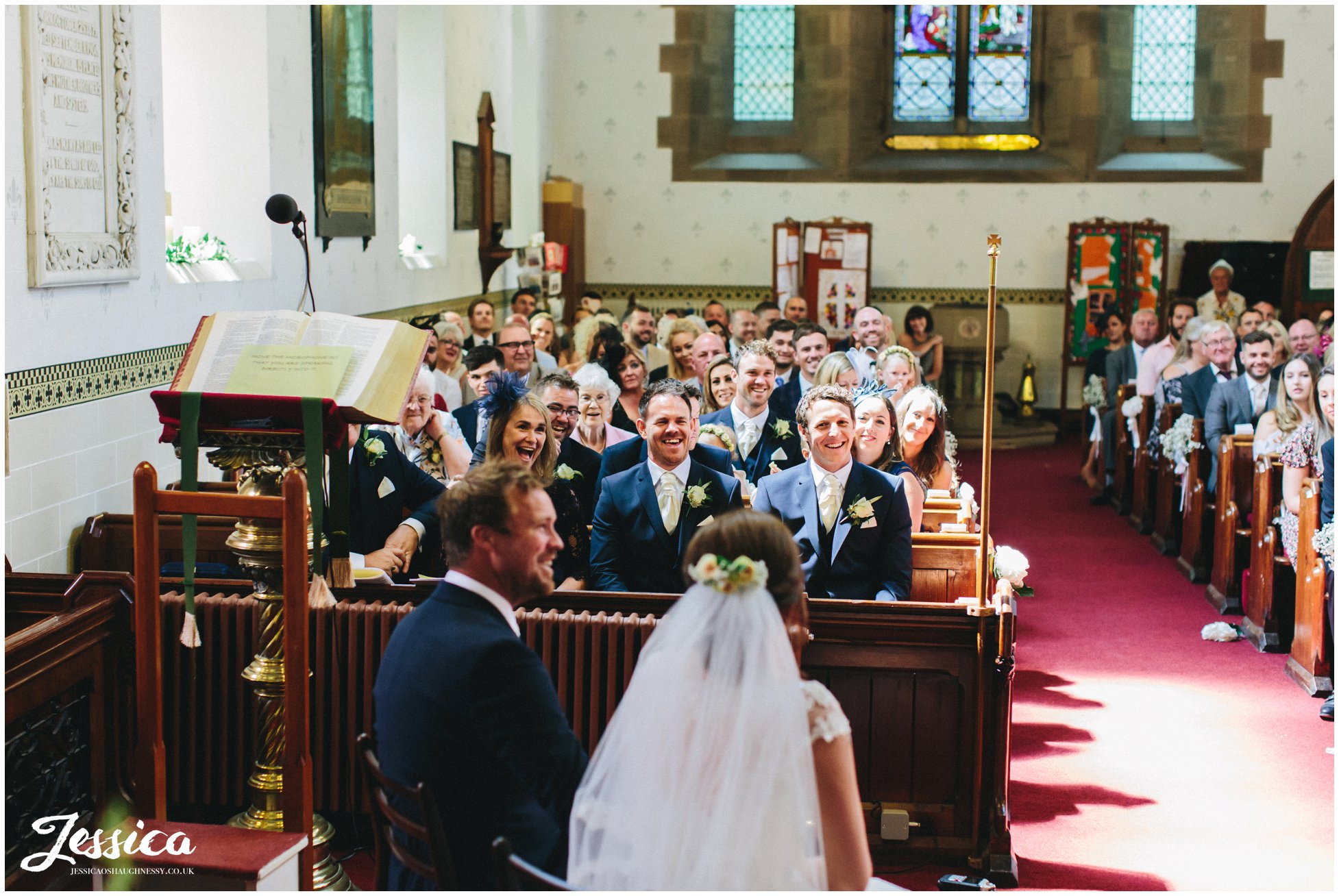 guests laugh during the wedding ceremony at st annes church in singleton