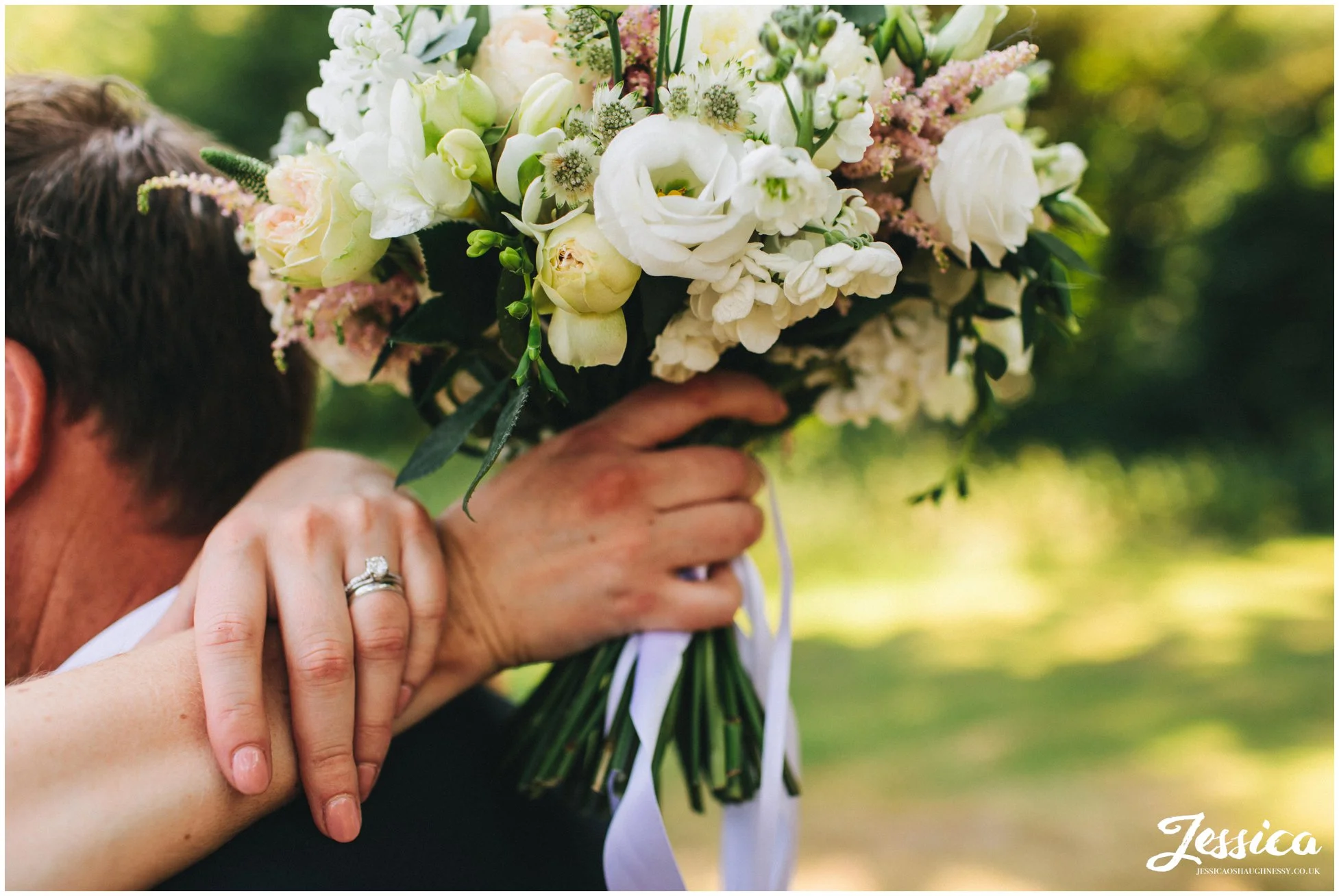 bride shows off her wedding rings and bride bouquet