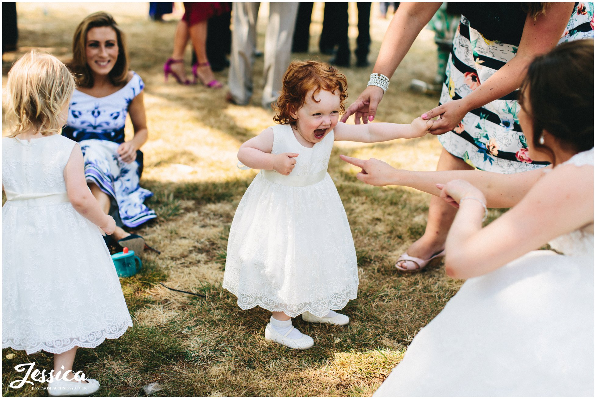 a flower girl laughs as the bride plays with her