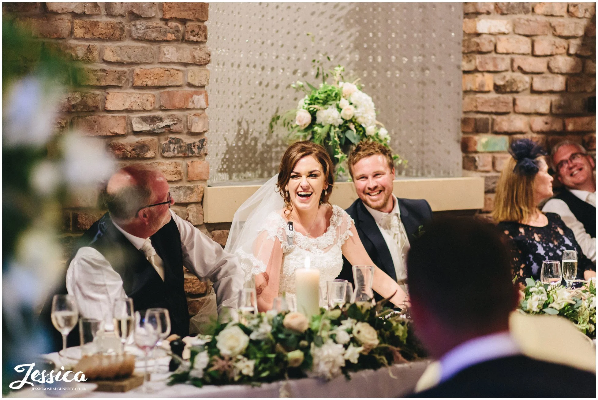 husband and wife laugh on the table table during their wedding speeches