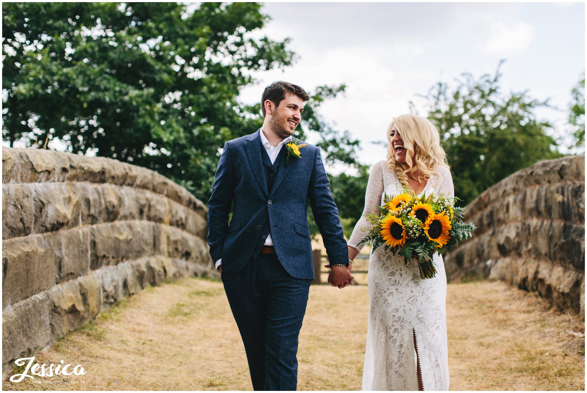 newly wed's hold hands walking over the bridge