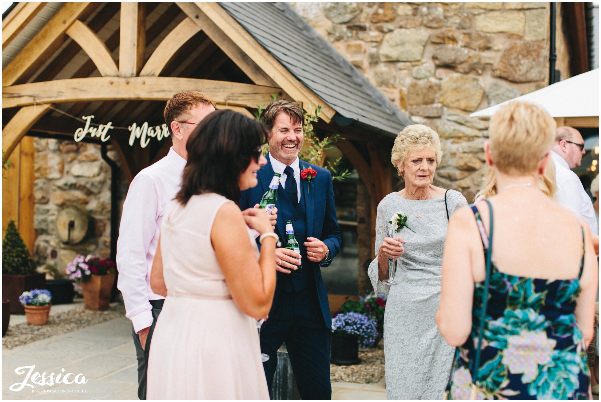 wedding guests laugh together at the drinks reception