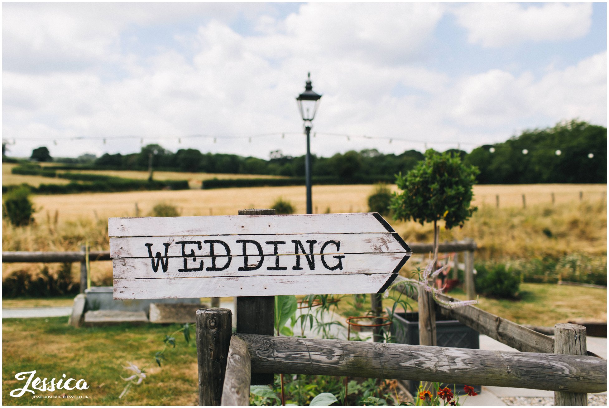 wedding sign pointing guests to the ceremony under the bridge