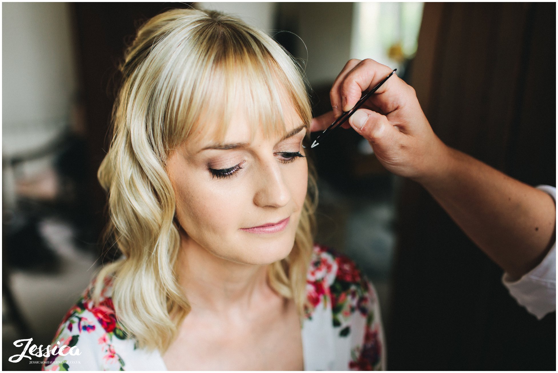 the bride has her makeup done on her wedding morning