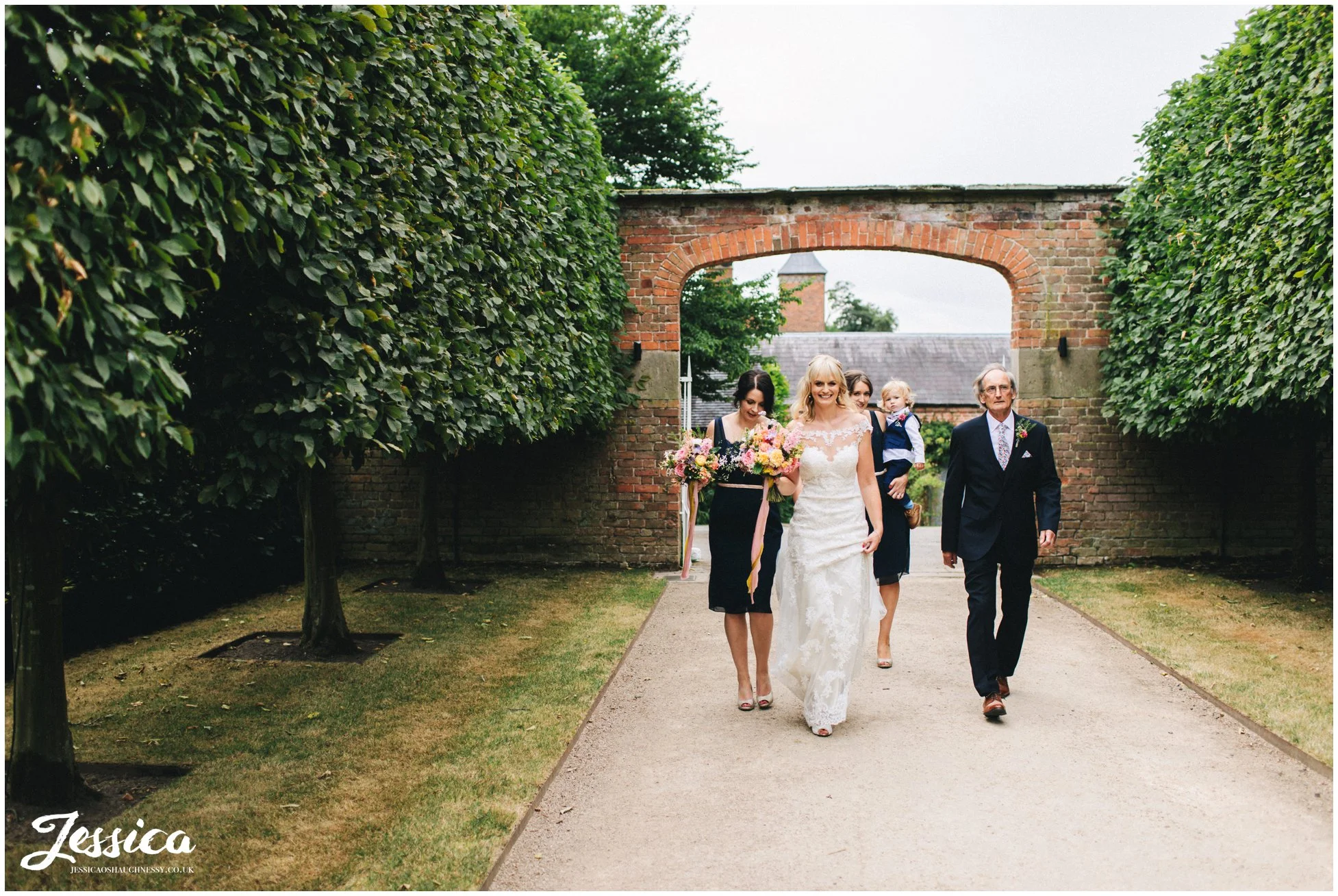 bride & her father walk down the tree lined path at combermere abbey