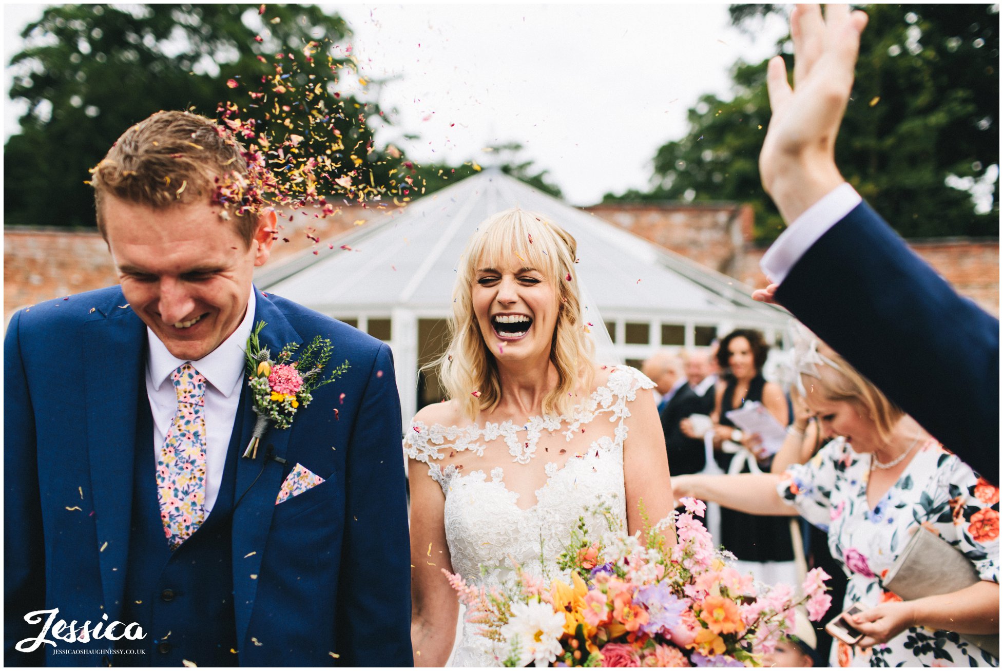 bride laughs as her guests throw confetti at her