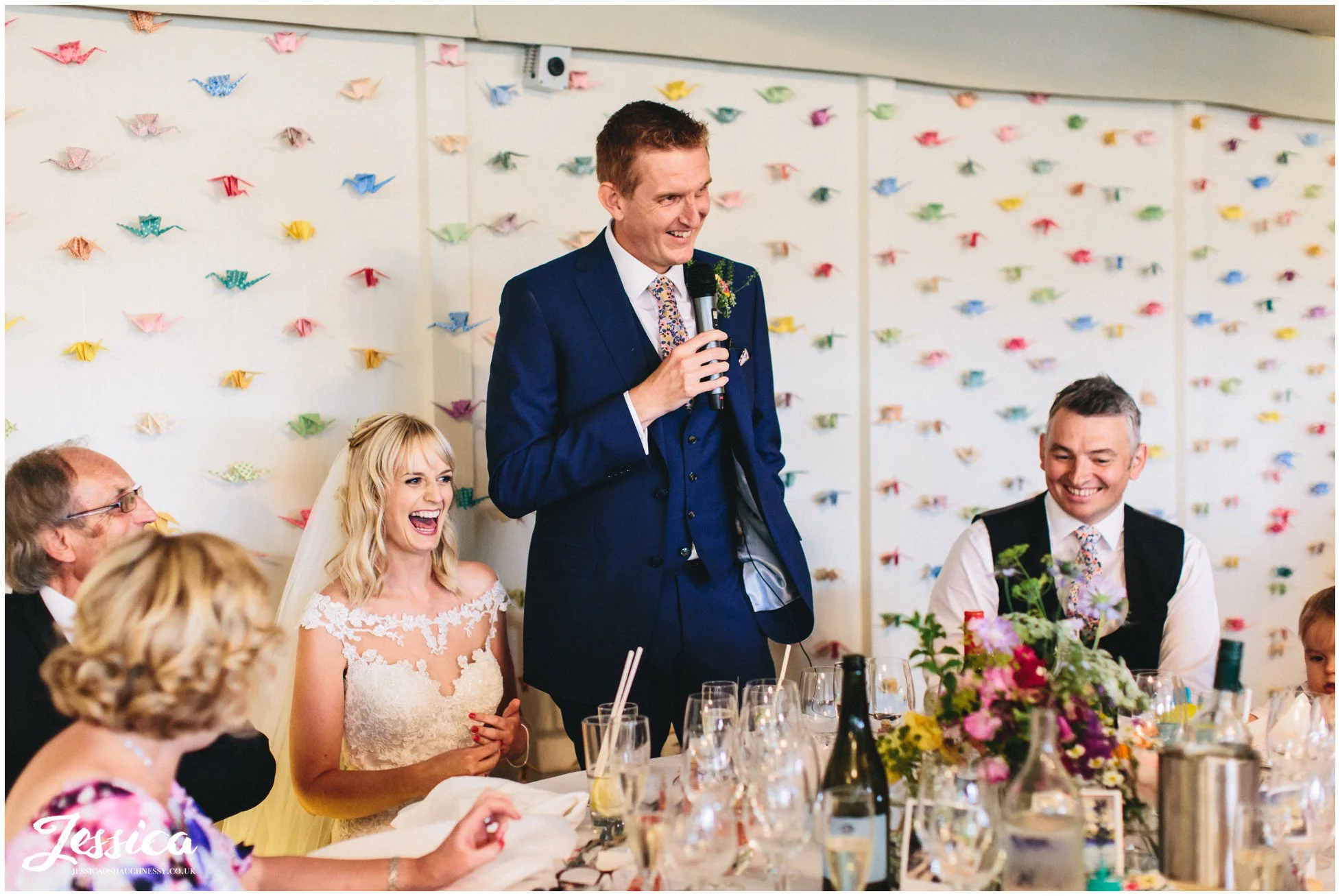 the groom gives his speech with paper cranes in the background