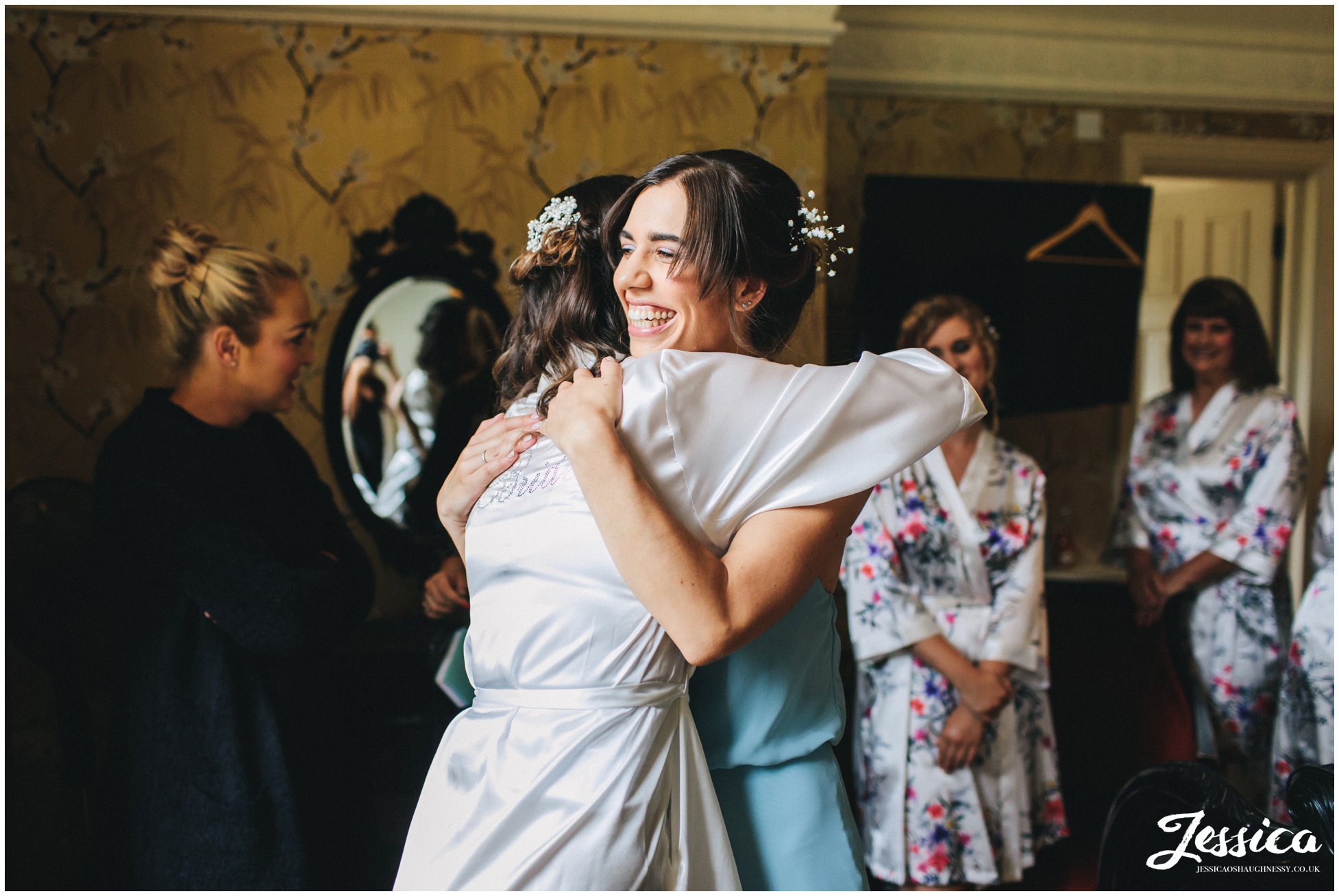 bride hugs her sister who is wearing her bridesmaid dress