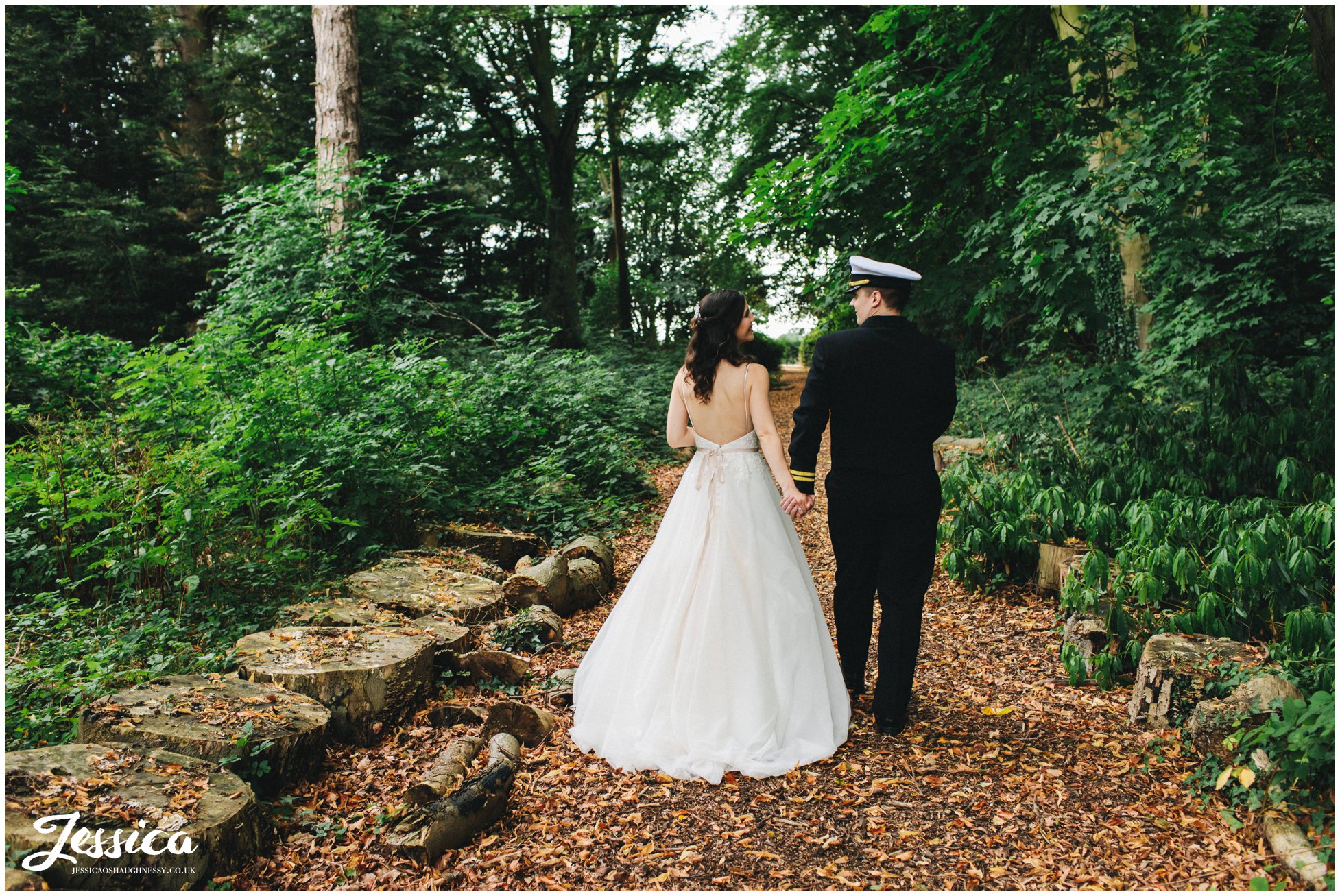 the new husband and wife hold hands walking through the forest