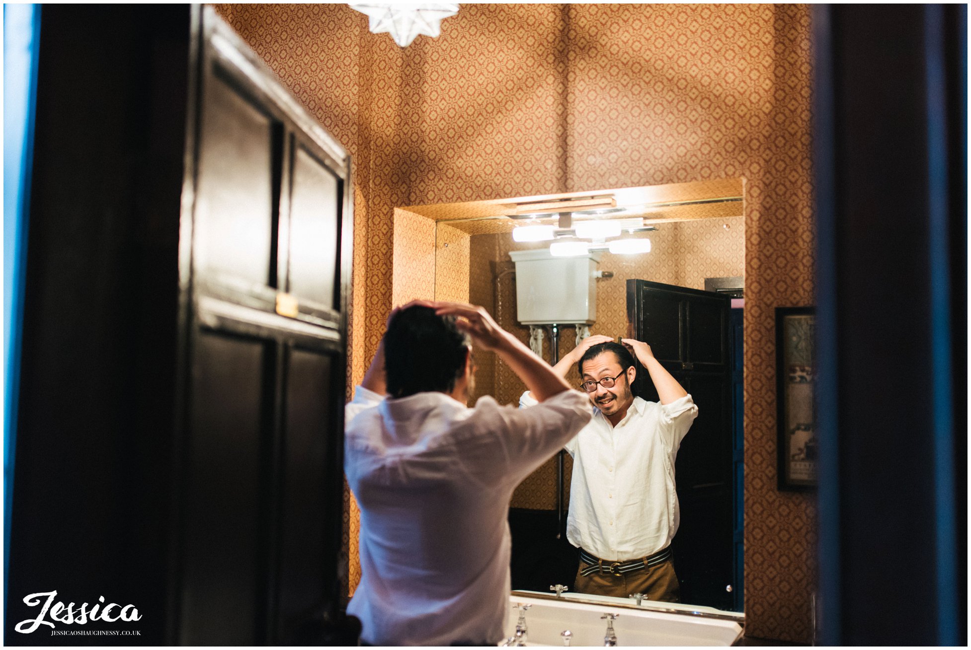 the groom does his hair ready for the wedding