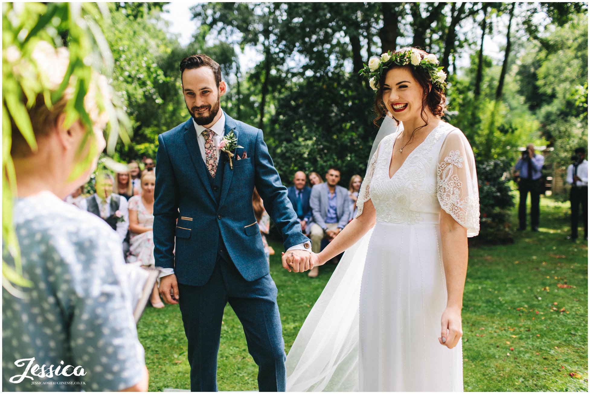 the couple hold hands during their stonyford cottage gardens wedding ceremony