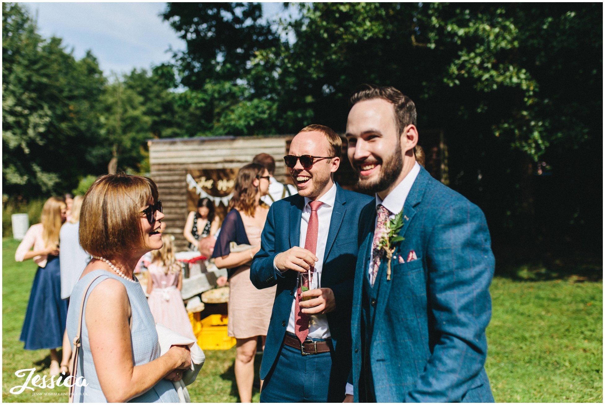 groom laughs with his friends in the sunshine
