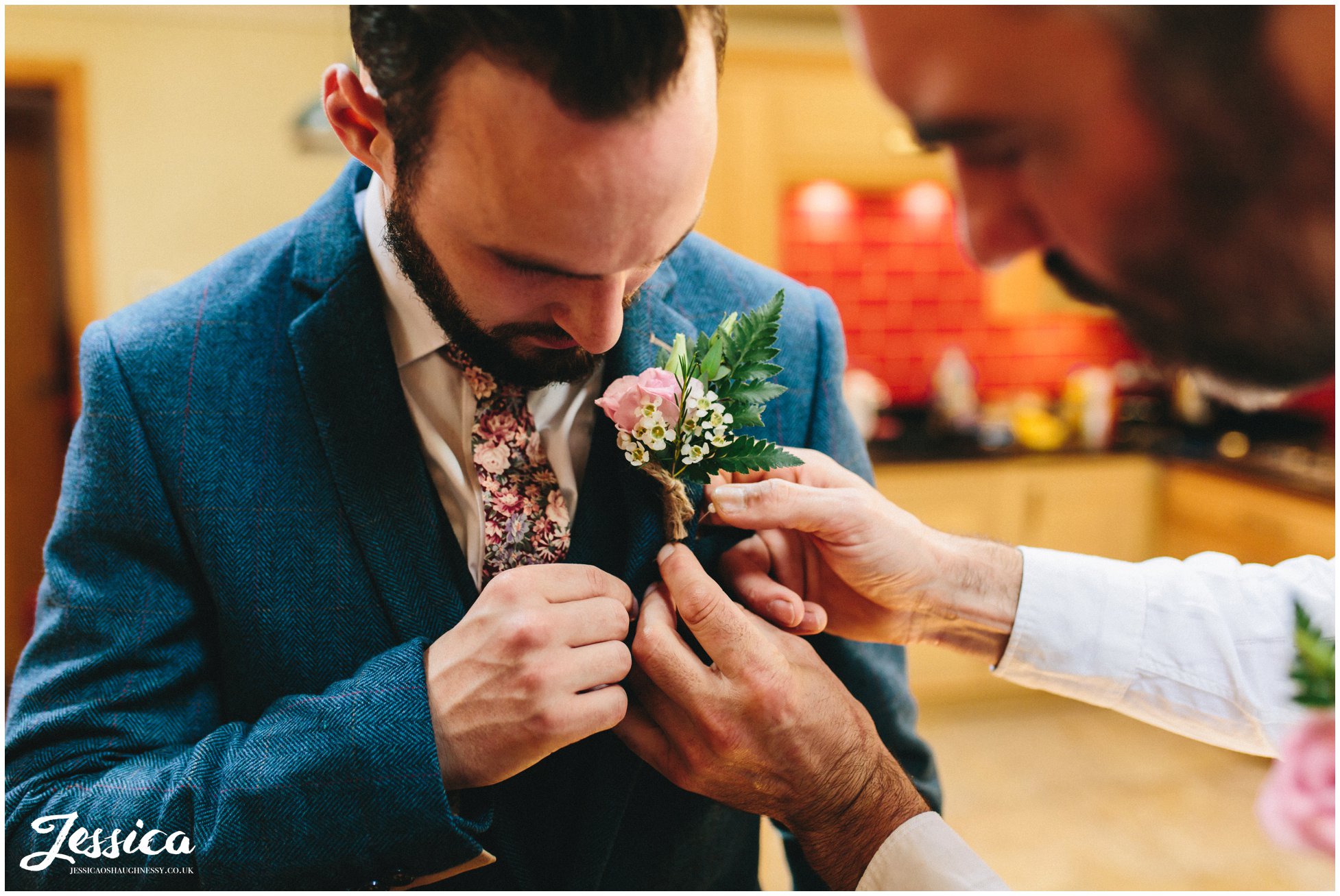 the groom's button hole is pinned on his jacket