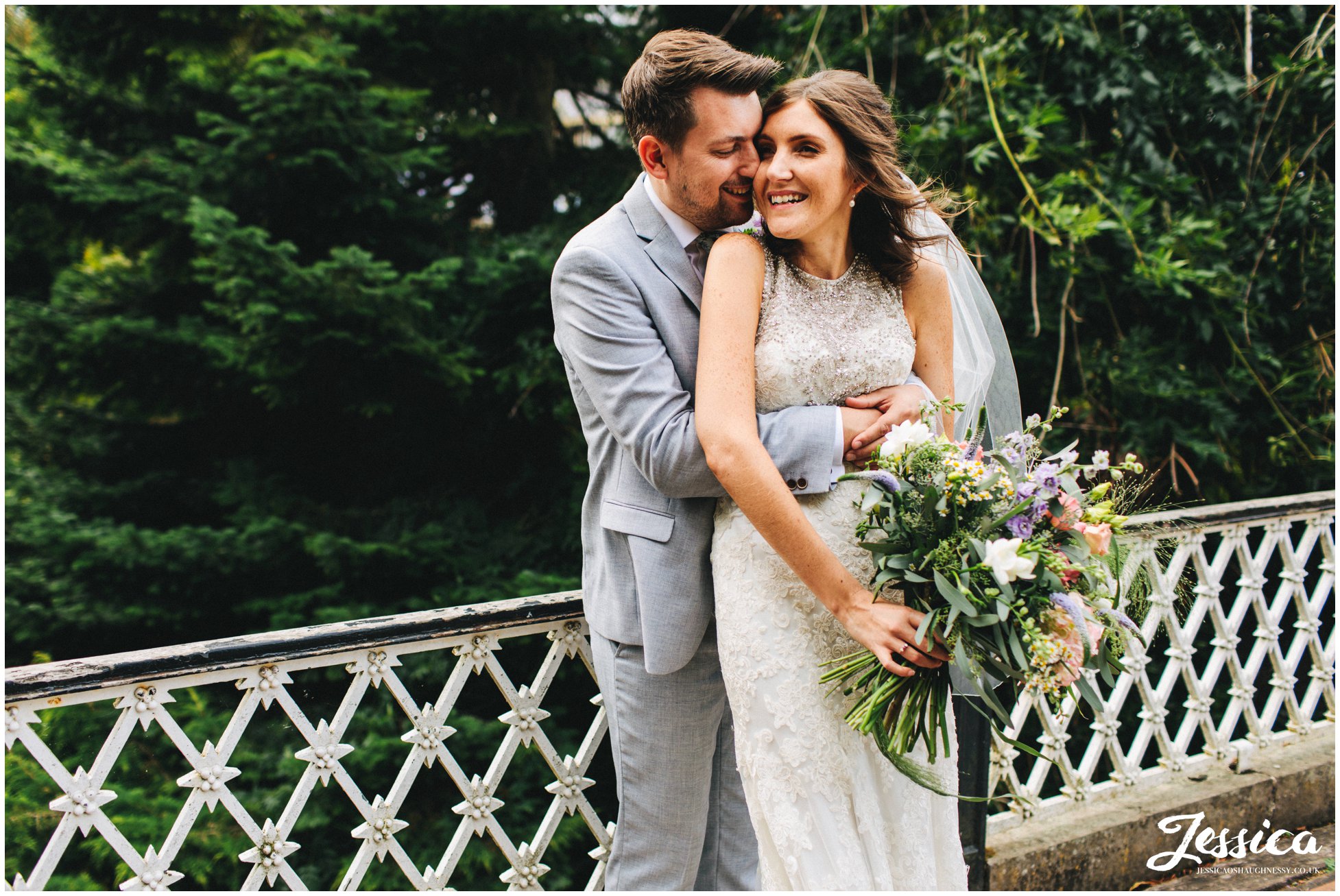 husband and wife hold each other on the bridge in buxton pavilion gardens