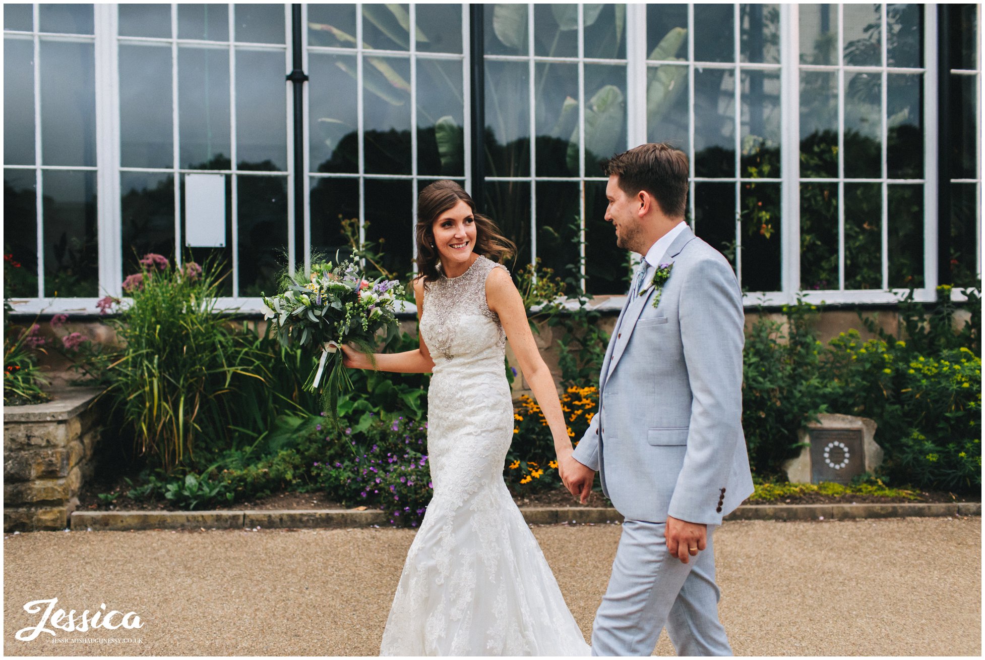 couple walk hand in hand along side the pavilion