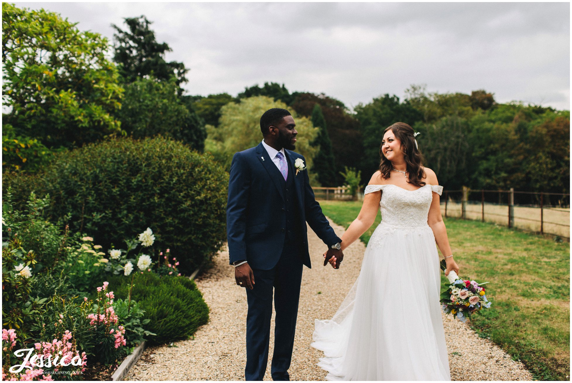 the couple walk through the gardens holding hands