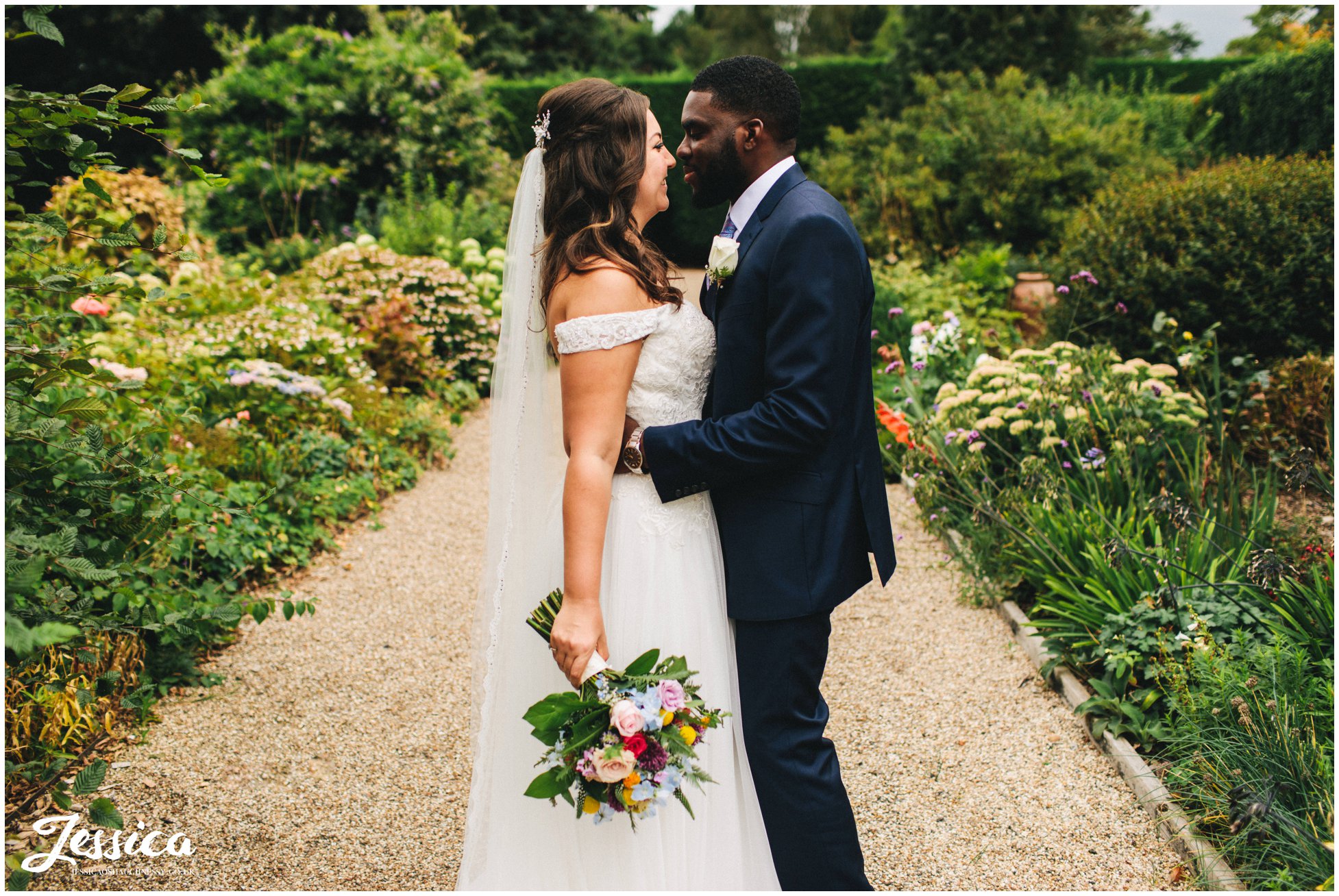 the bride and groom kiss in gaynes park gardens