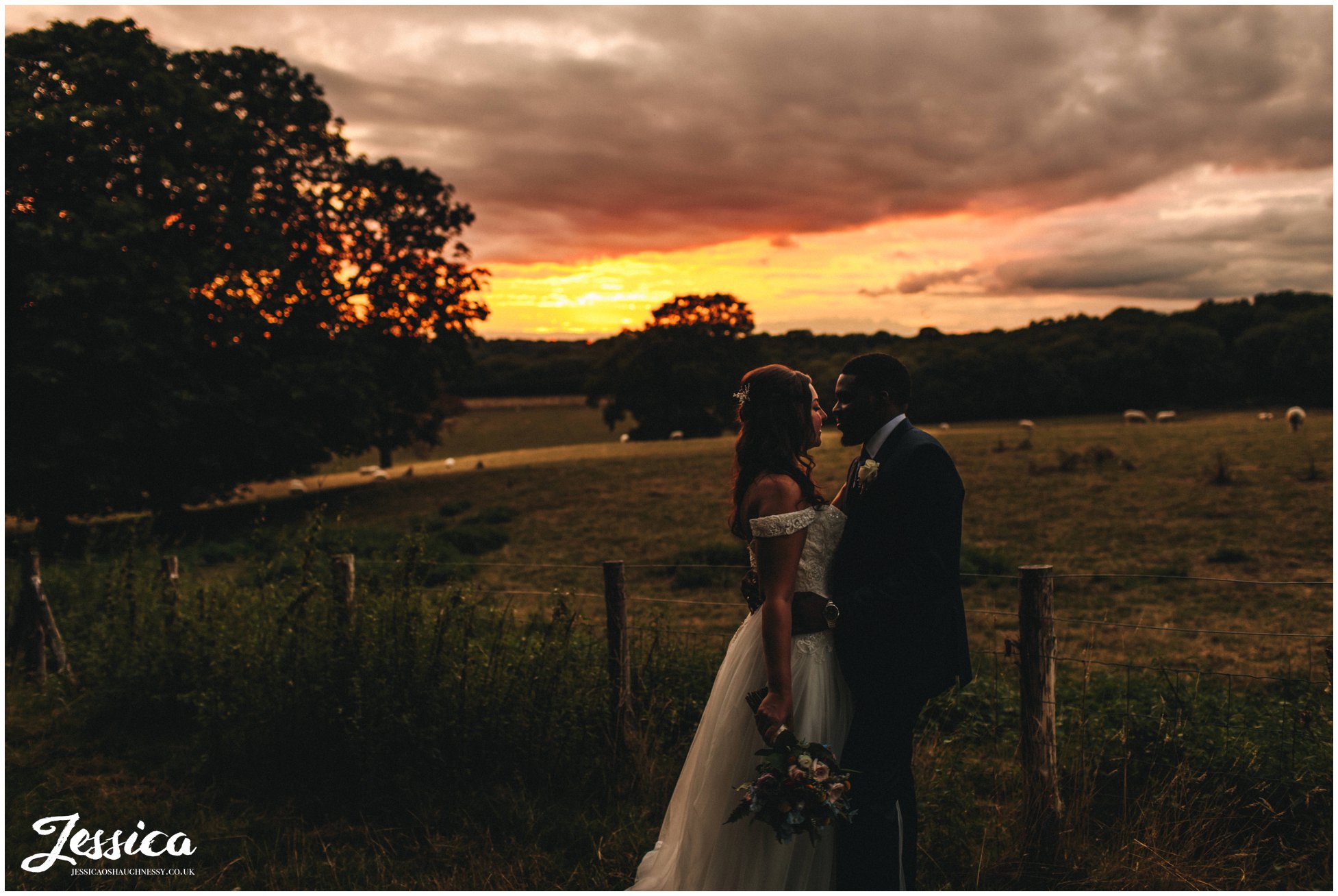 the couple stand in front of the sunset at gaynes park in epping