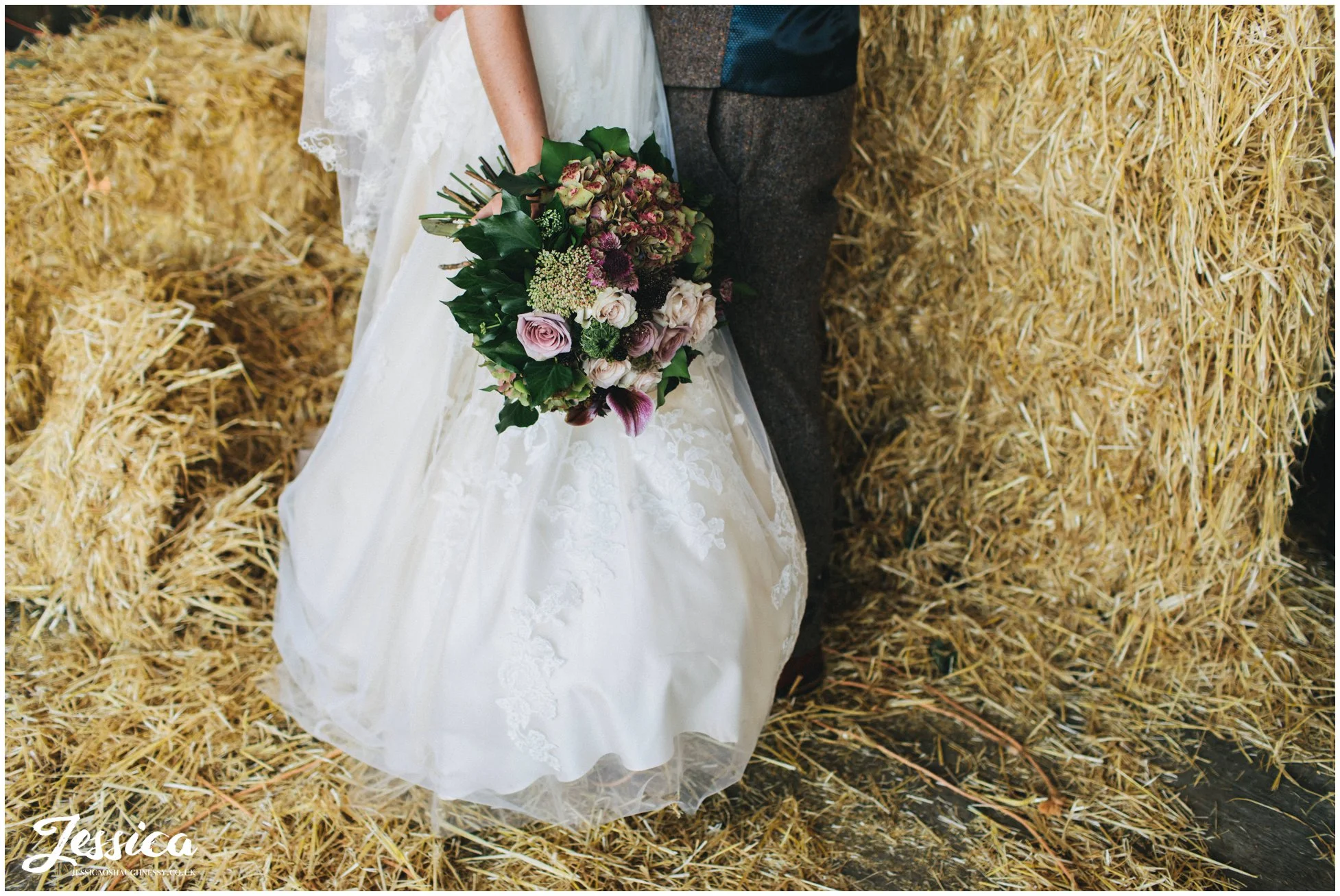 bride holds her flowers next to the hay bales