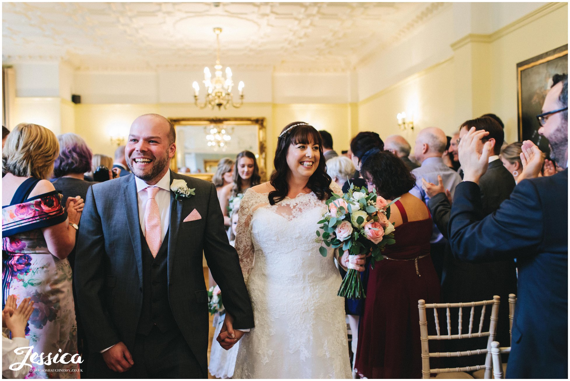 husband and wife hold hands and walk back down the aisle