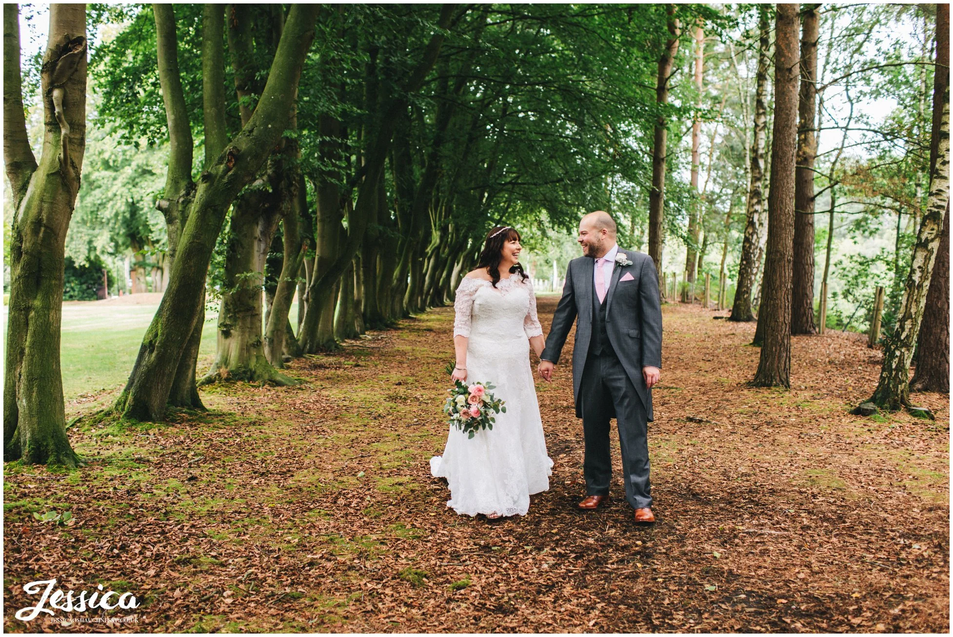 bride & groom hold hands walking through the trees