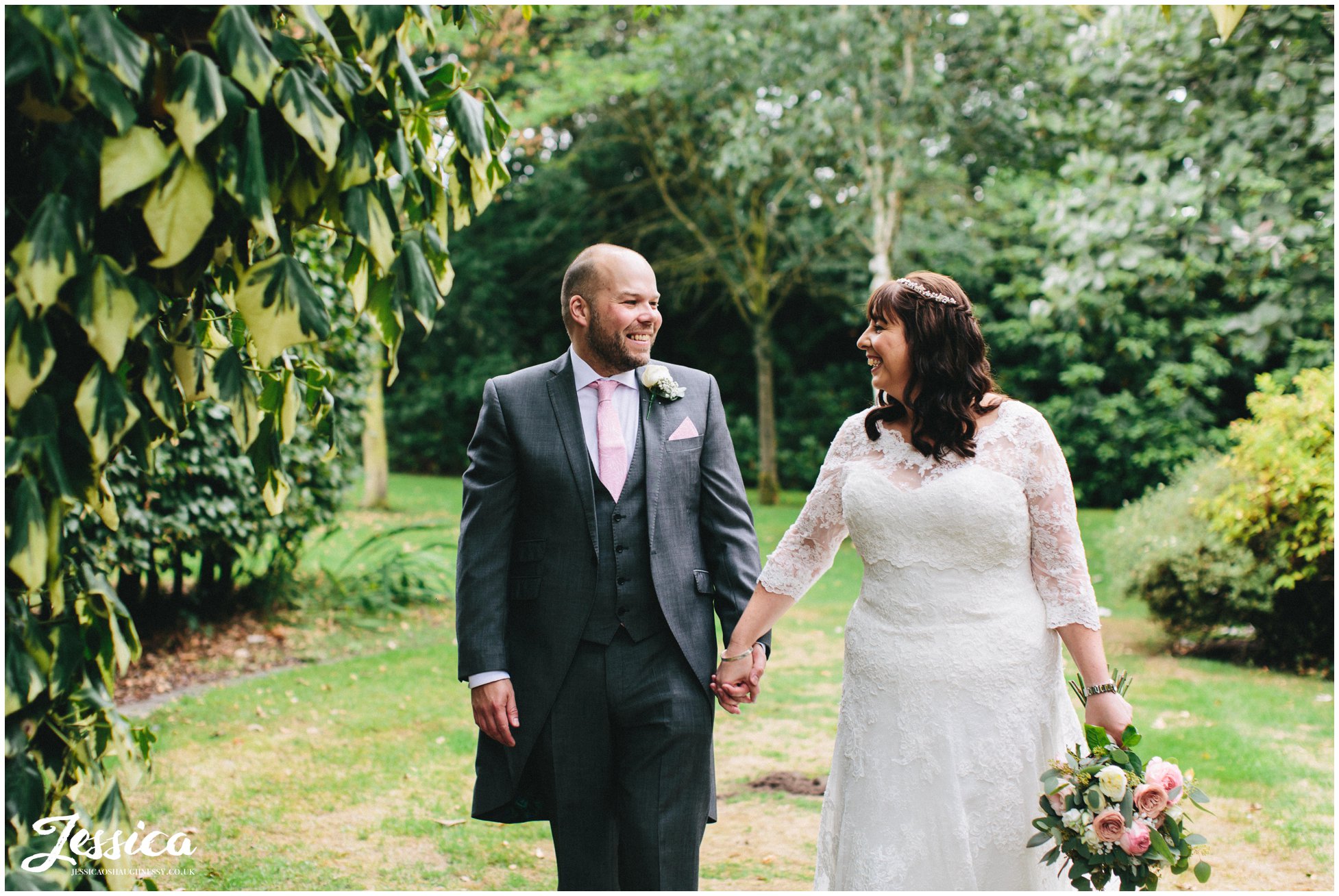 husband and wife hold hands and walk through the grounds of the cheshire wedding venue