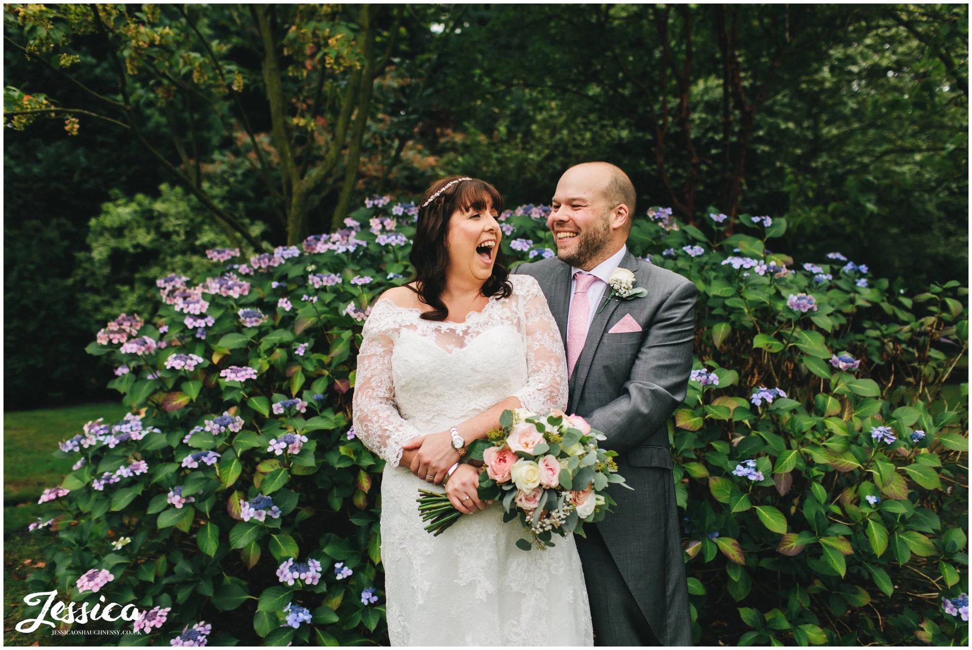 the couple laughing together in front of the flowers