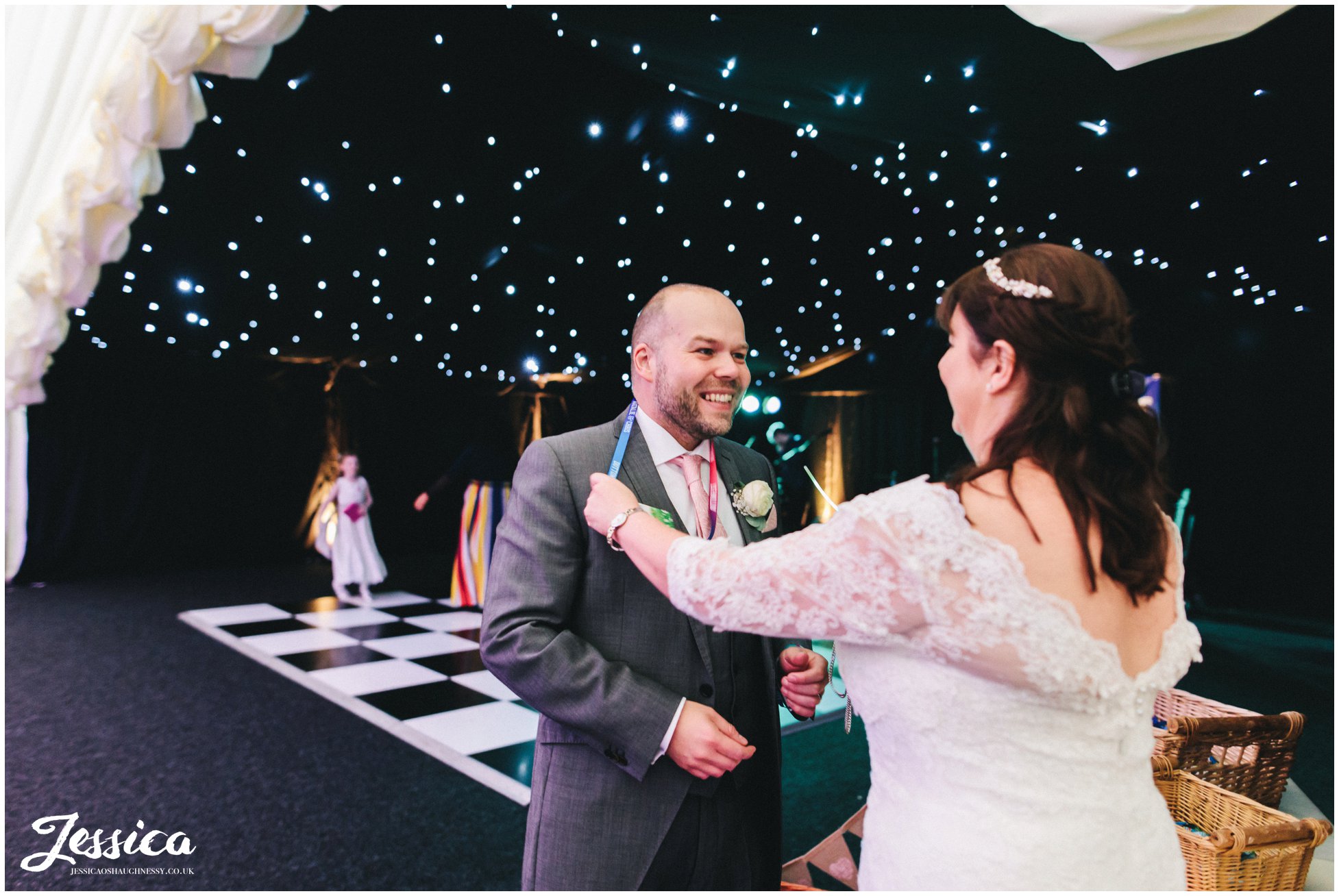 the bride puts festival lanyard on the groom