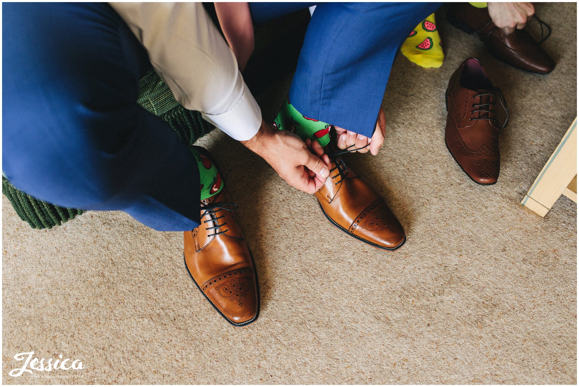 the groom puts on his shoes over brightly coloured socks